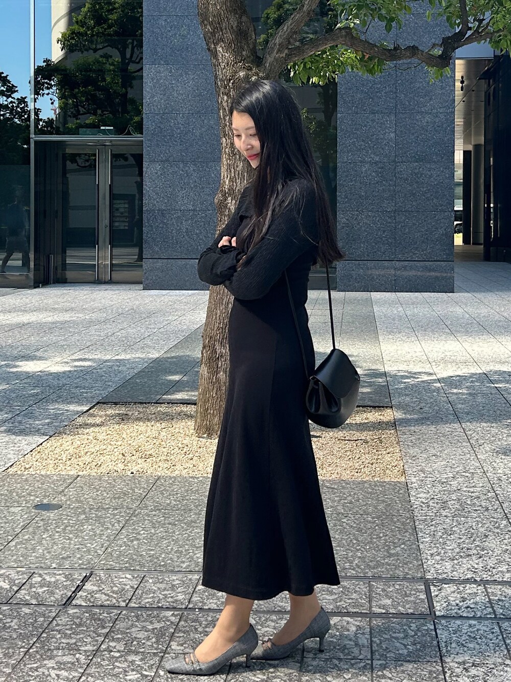 ブラック系のワンピース、ブラック系のパンプス、ブラック系のショルダーバッグを着用したレディースの秋コーディネートの2枚目の写真