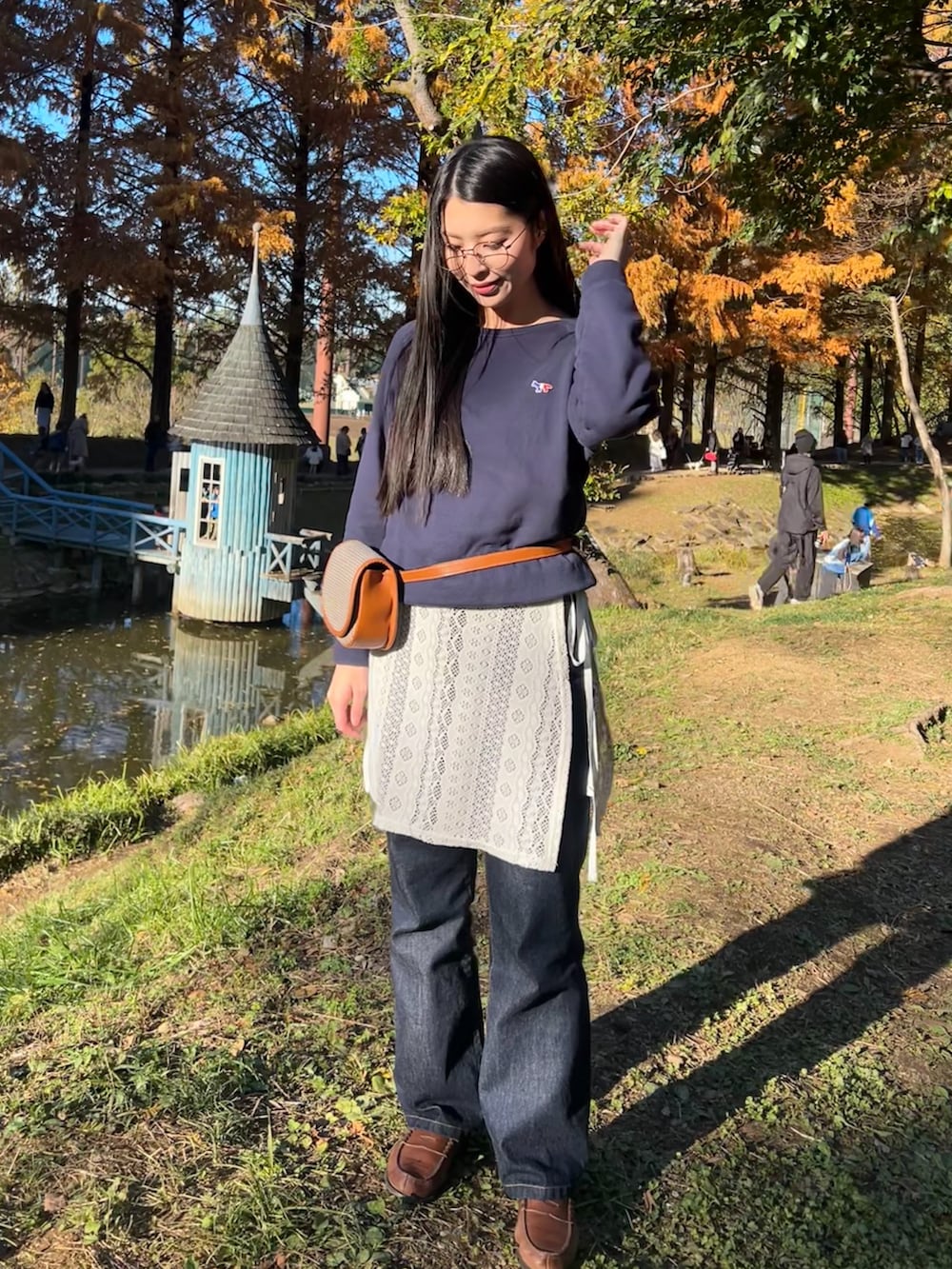 ブルー系のスウェット、ブラウン系のボディバッグ/ウエストポーチ、ホワイト系のスカートを着用したレディースの秋コーディネートの2枚目の写真