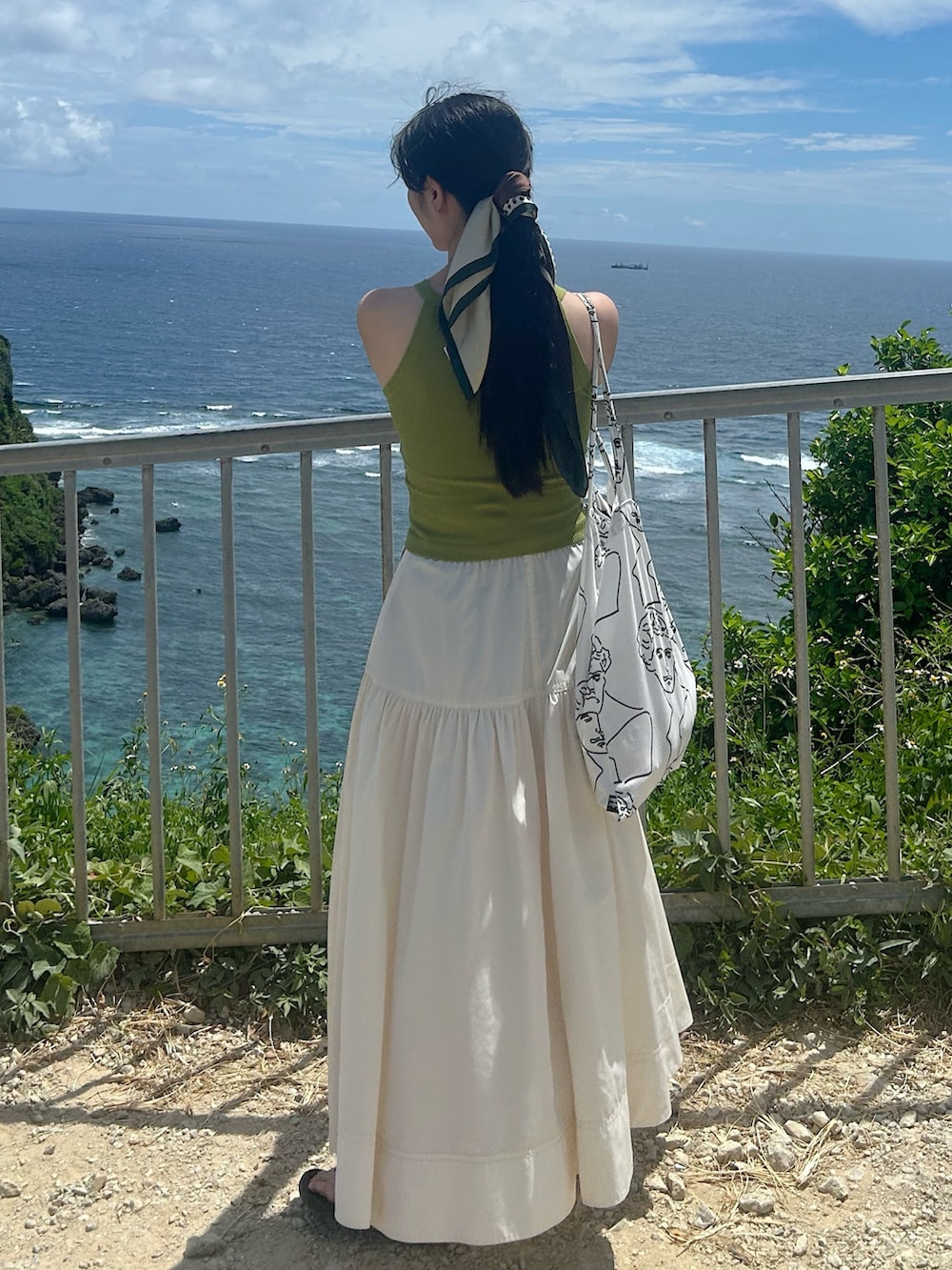 グリーン系のタンクトップ、ホワイト系のスカート、ホワイト系のトートバッグを着用したレディースの夏コーディネートの2枚目の写真