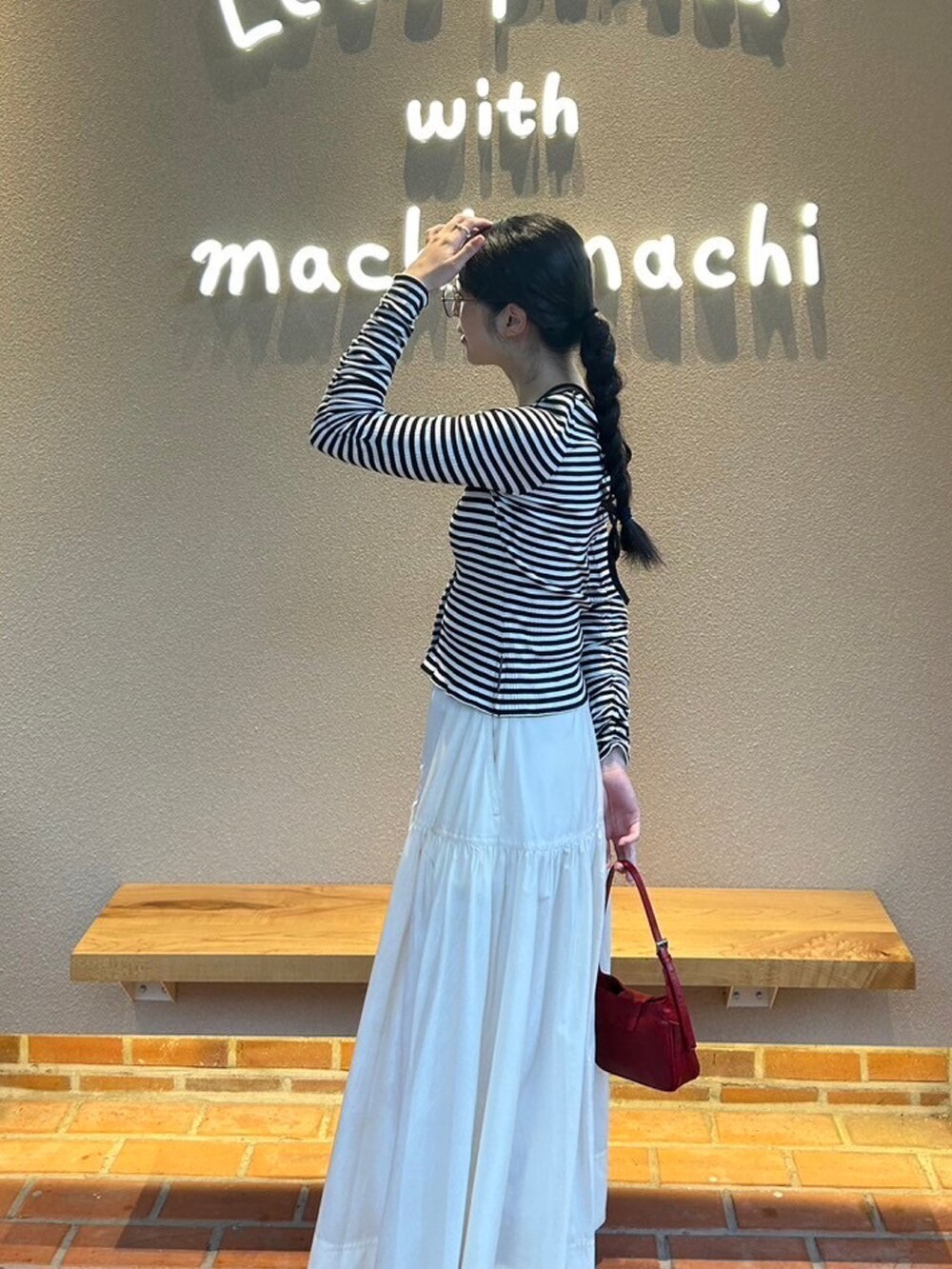 ホワイト系のスカート、レッド系のハンドバッグ、ホワイト系のパンプスを着用したレディースの春コーディネートの2枚目の写真