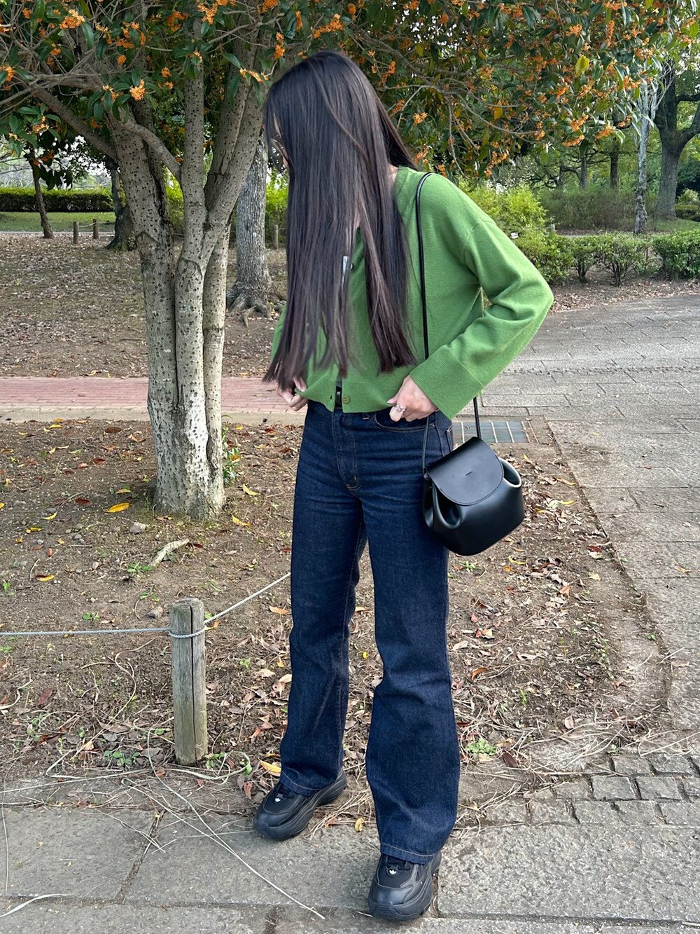 ブラック系のスニーカー、ホワイト系のキャミソール、ブルー系のデニムパンツを着用したレディースの秋コーディネートの2枚目の写真