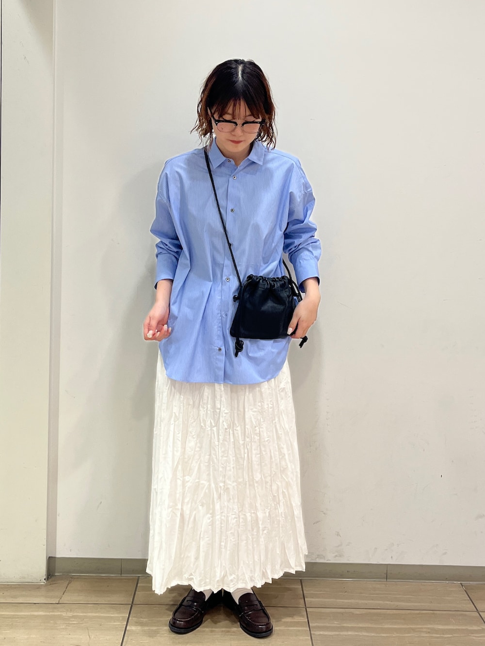 ホワイト系のスカート、ブルー系のシャツ/ブラウス、ブラック系のショルダーバッグを着用したレディースの冬コーディネートの2枚目の写真