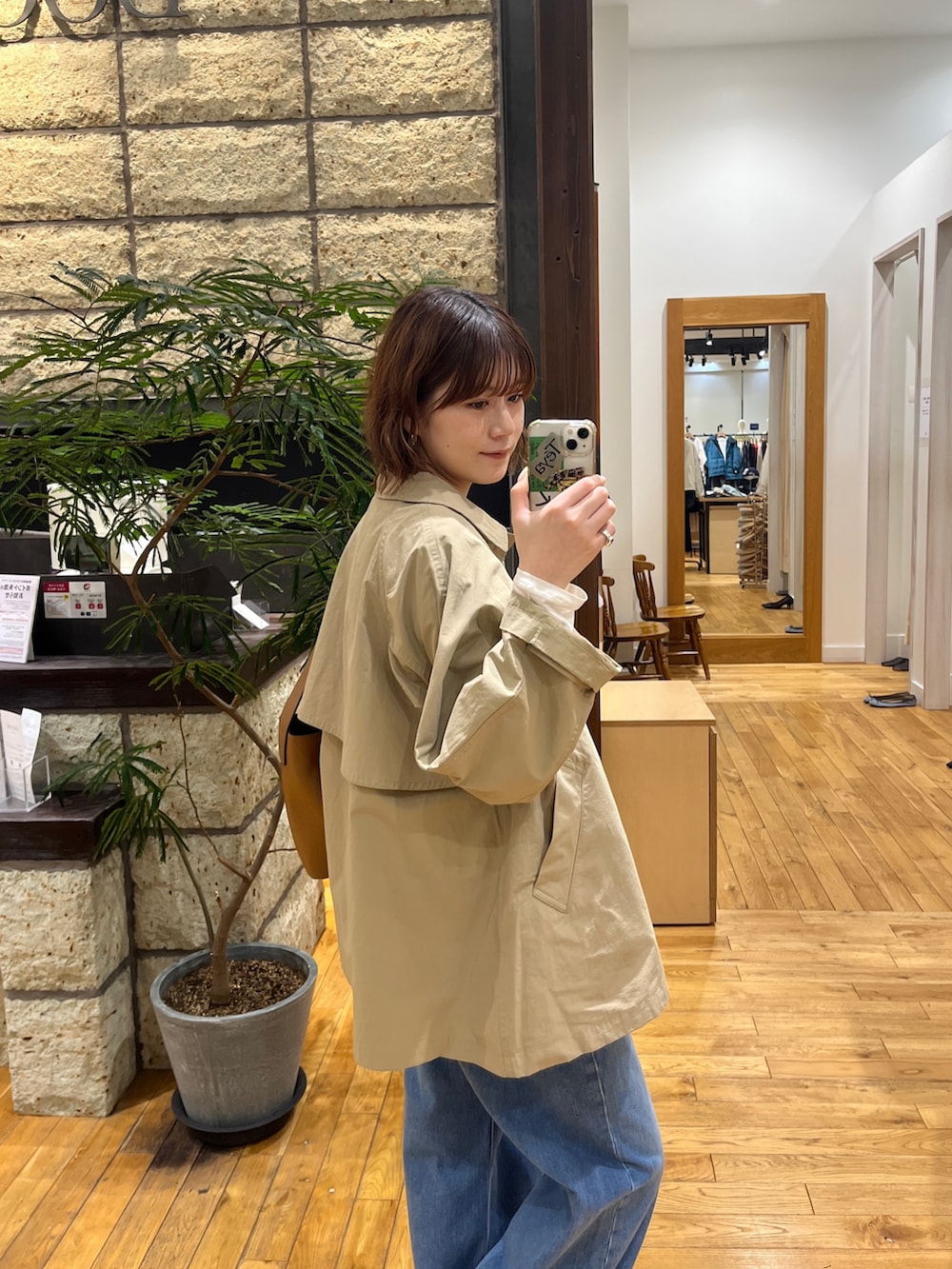 ベージュ系のステンカラーコート、ブルー系のベスト、ホワイト系のTシャツ/カットソーを着用したレディースの冬コーディネートの6枚目の写真