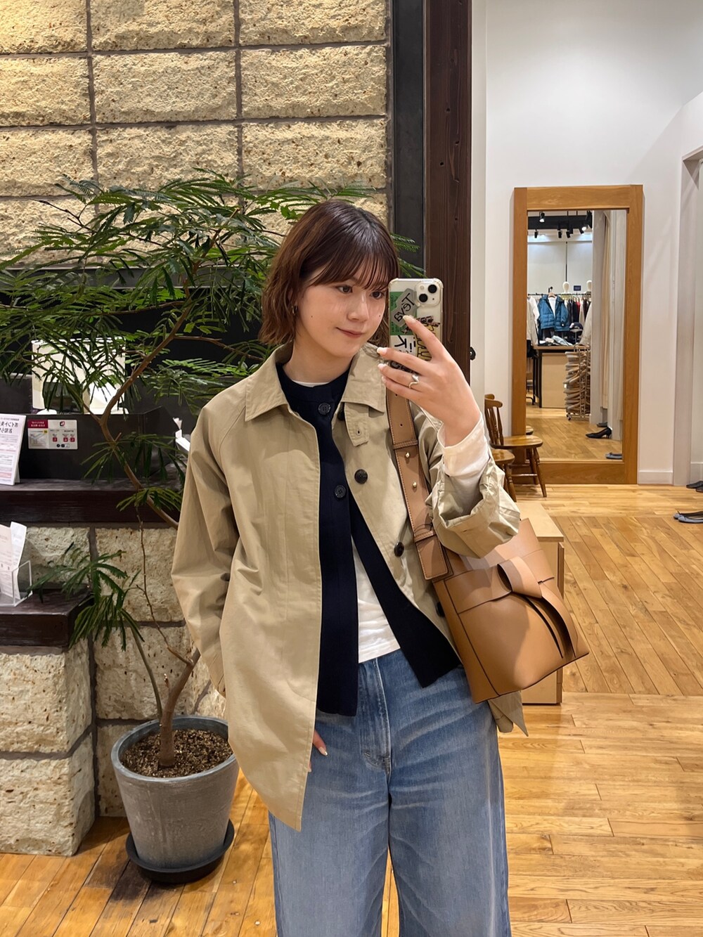 ベージュ系のステンカラーコート、ブルー系のベスト、ホワイト系のTシャツ/カットソーを着用したレディースの冬コーディネートの7枚目の写真