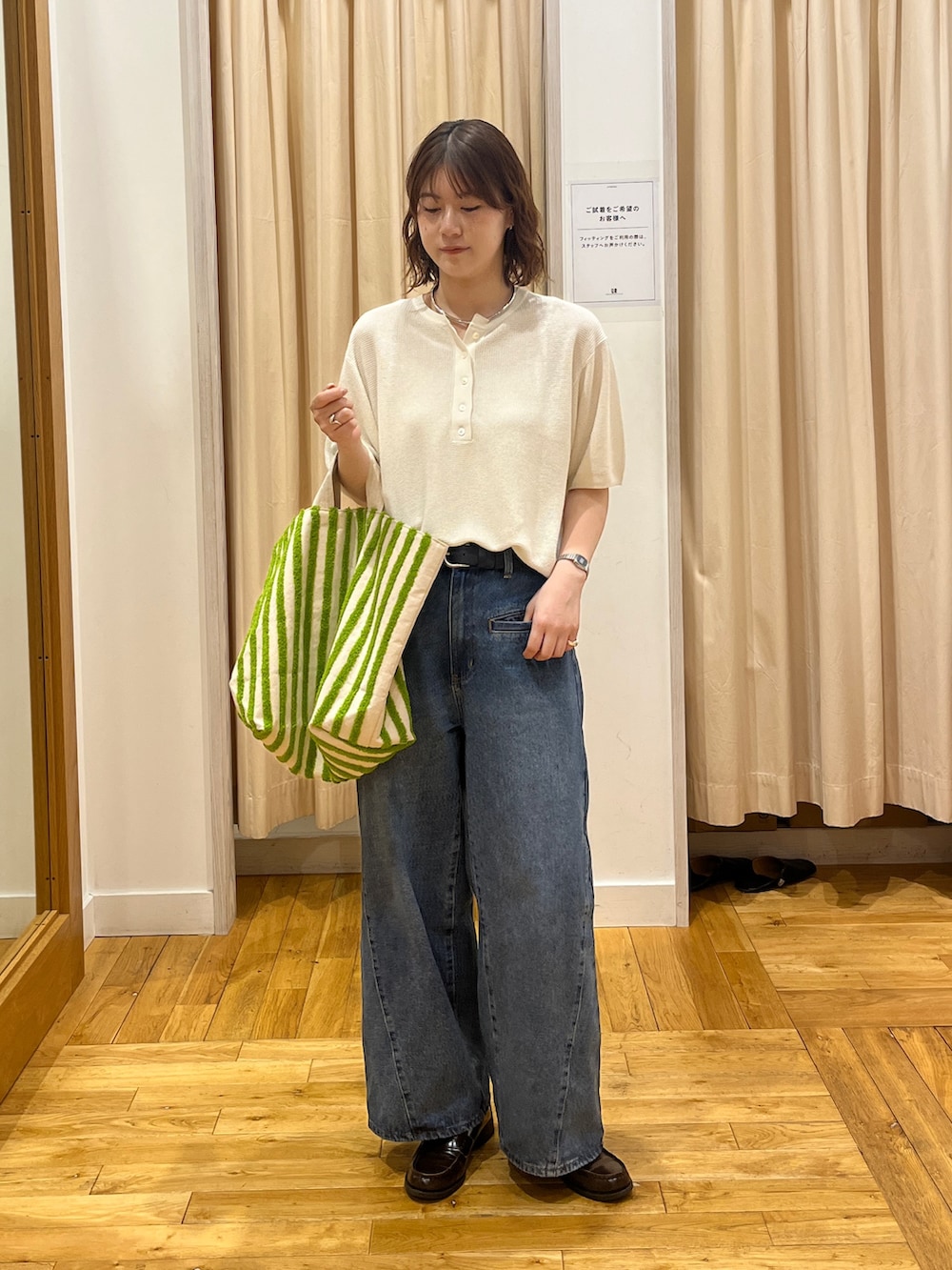 ブルー系のデニムパンツ、ホワイト系のニット/セーター、グリーン系のトートバッグを着用したレディースの春コーディネートの2枚目の写真