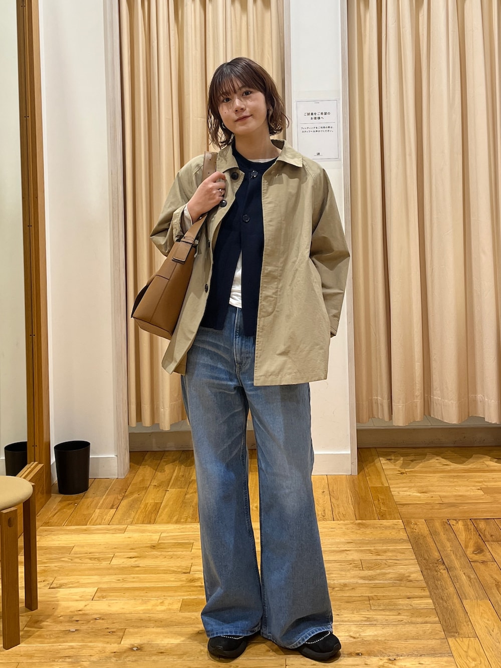 ベージュ系のステンカラーコート、ブルー系のベスト、ホワイト系のTシャツ/カットソーを着用したレディースの冬コーディネートの3枚目の写真