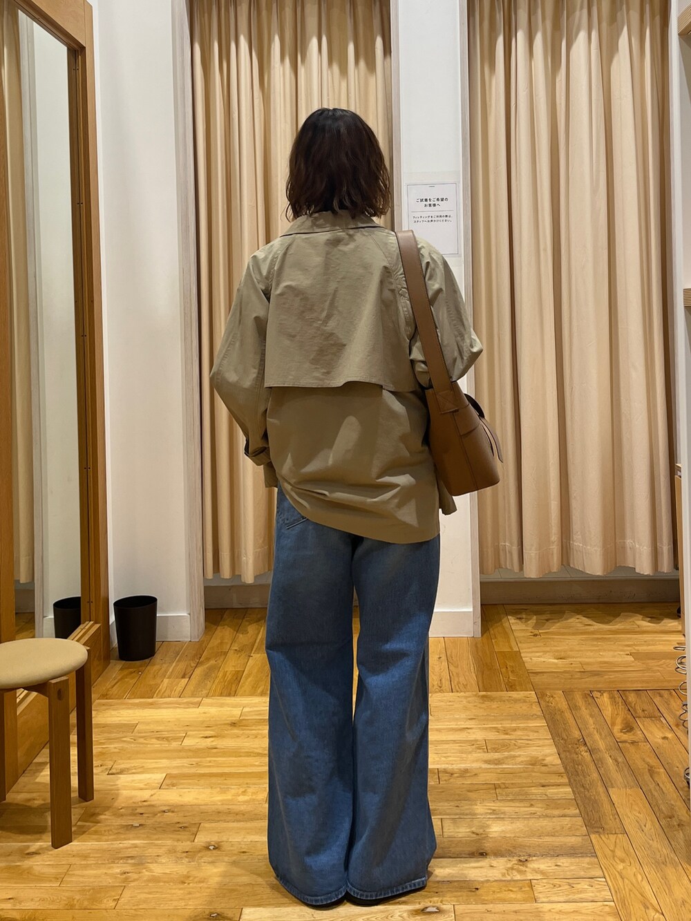 ベージュ系のステンカラーコート、ブルー系のベスト、ホワイト系のTシャツ/カットソーを着用したレディースの冬コーディネートの5枚目の写真