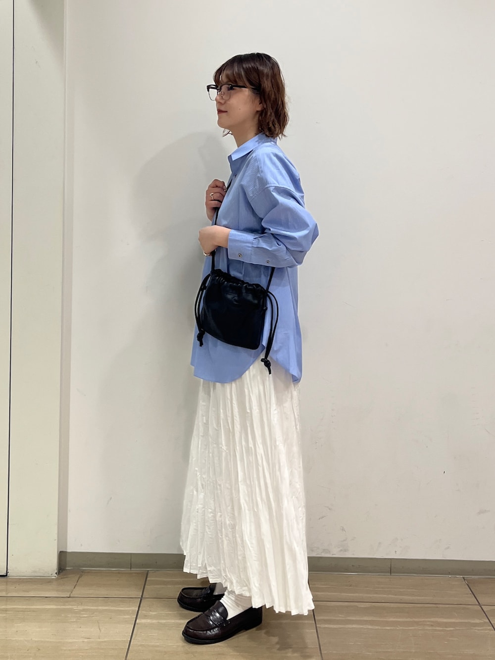 ホワイト系のスカート、ブルー系のシャツ/ブラウス、ブラック系のショルダーバッグを着用したレディースの冬コーディネートの3枚目の写真