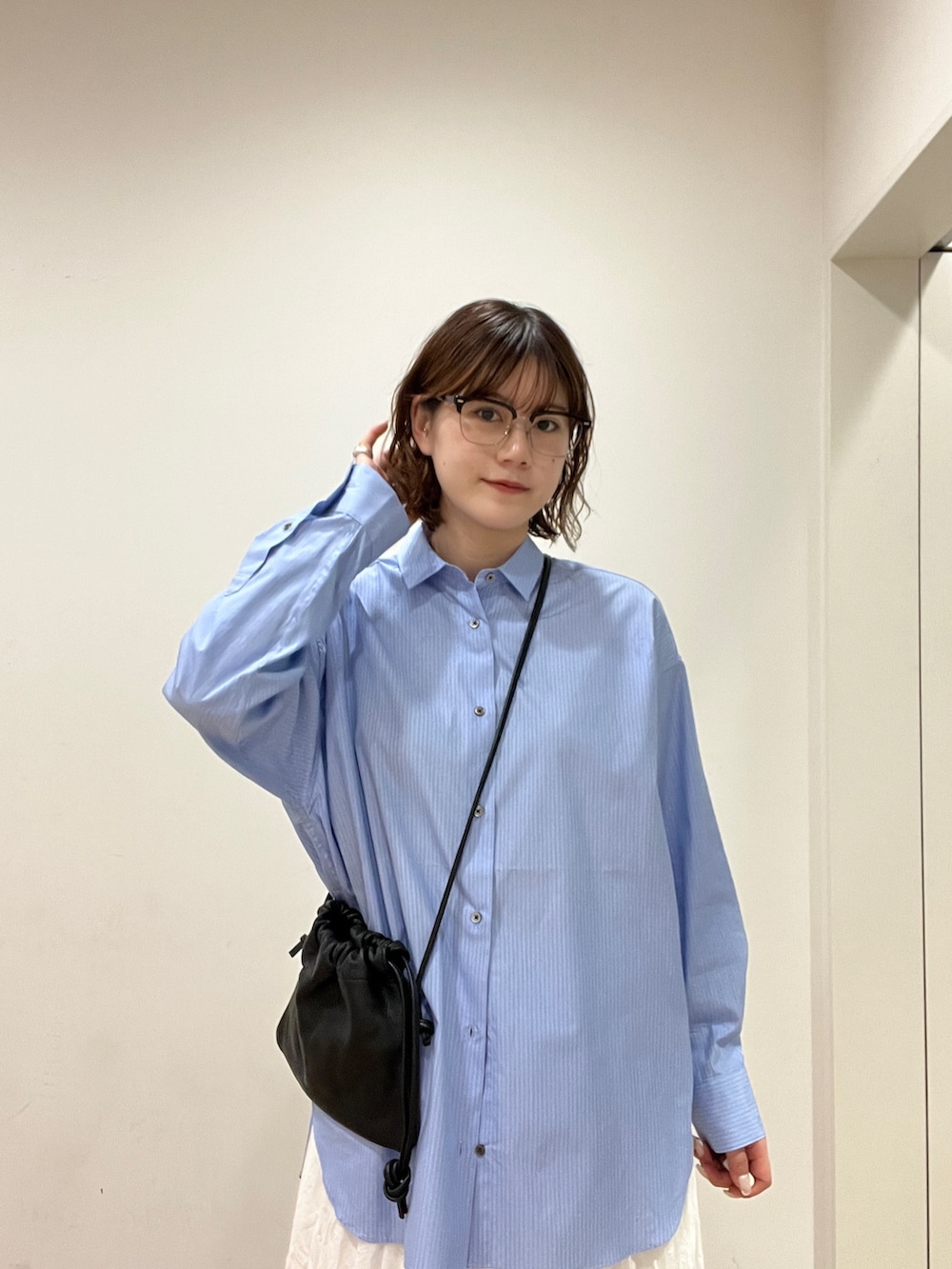 ホワイト系のスカート、ブルー系のシャツ/ブラウス、ブラック系のショルダーバッグを着用したレディースの冬コーディネートの6枚目の写真