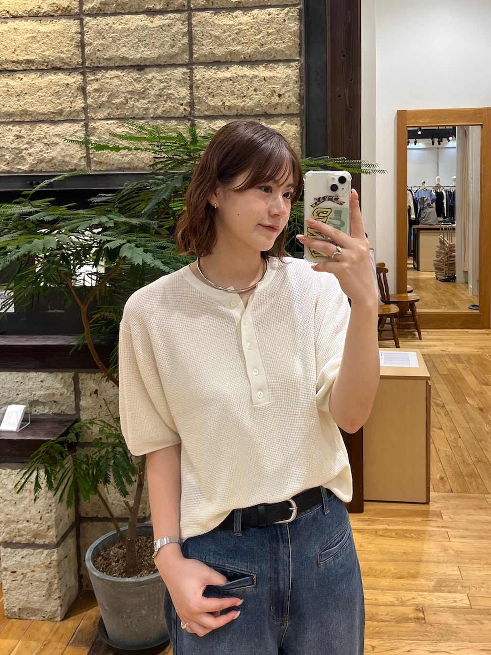 ブルー系のデニムパンツ、ホワイト系のニット/セーター、グリーン系のトートバッグを着用したレディースの春コーディネートの3枚目の写真