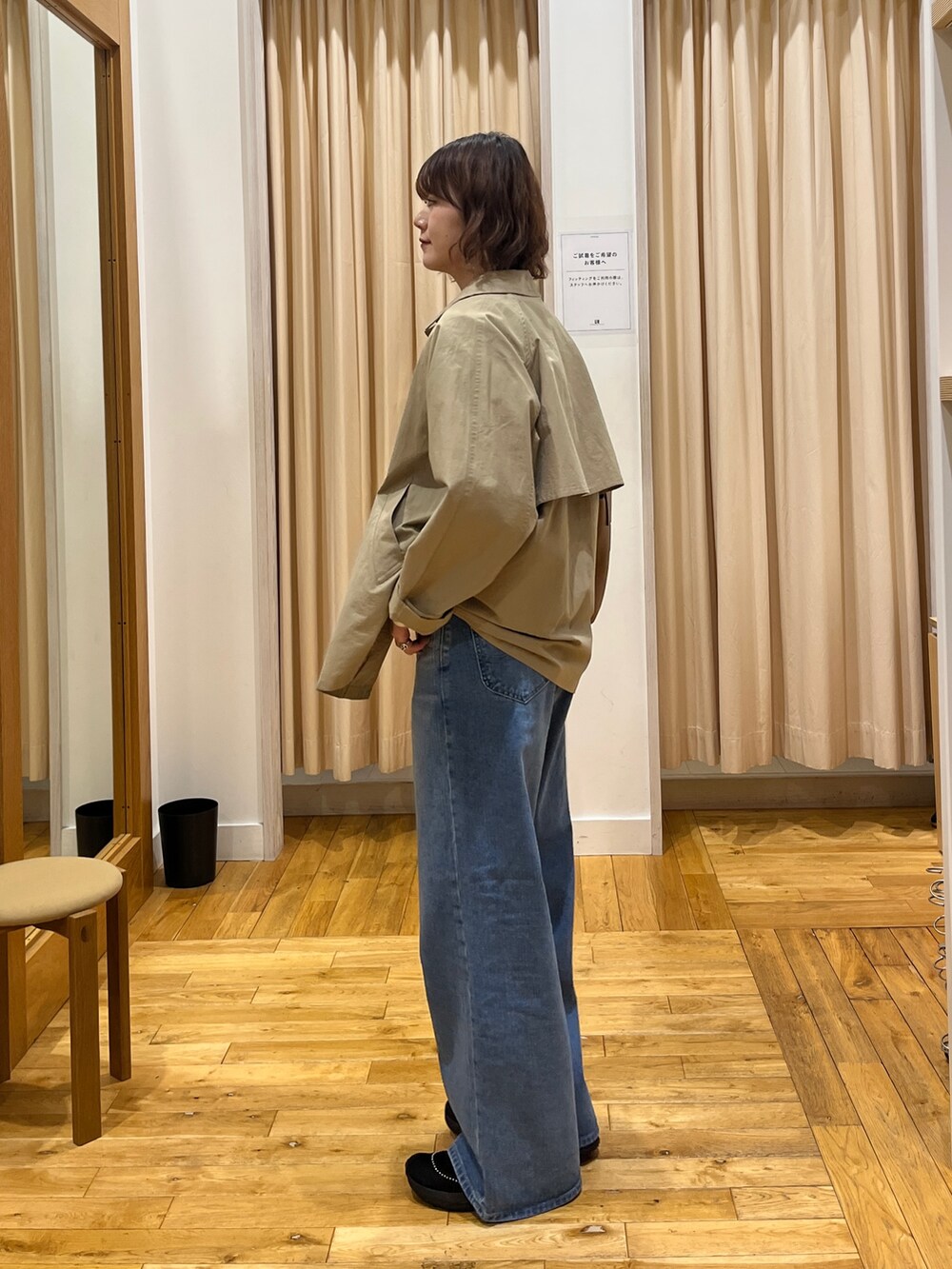 ベージュ系のステンカラーコート、ブルー系のベスト、ホワイト系のTシャツ/カットソーを着用したレディースの冬コーディネートの4枚目の写真