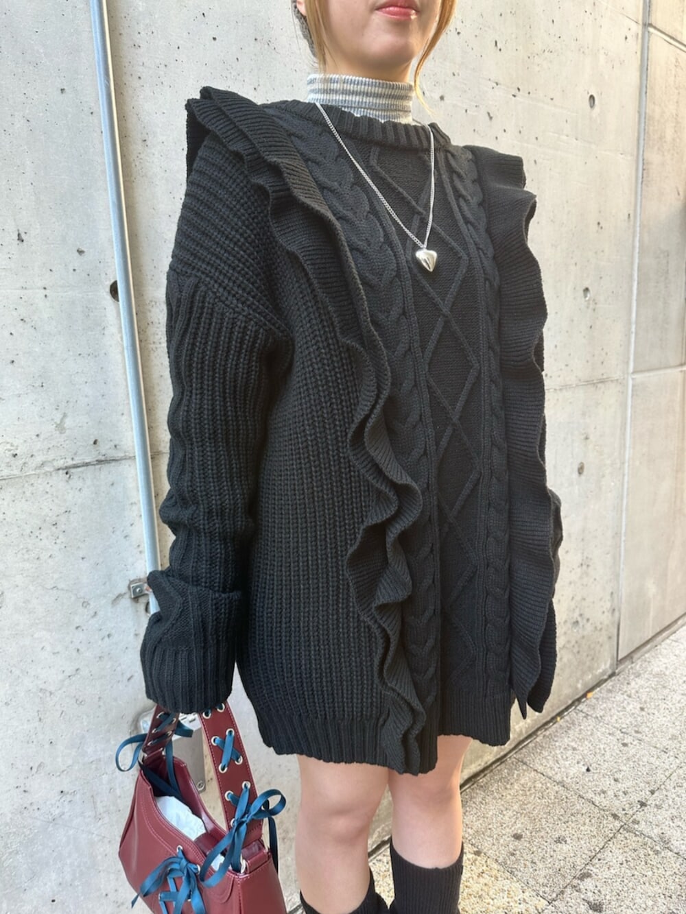 ブラック系のスニーカー、ブラック系のニット/セーター、レッド系のハンドバッグを着用したレディースの冬コーディネートの6枚目の写真