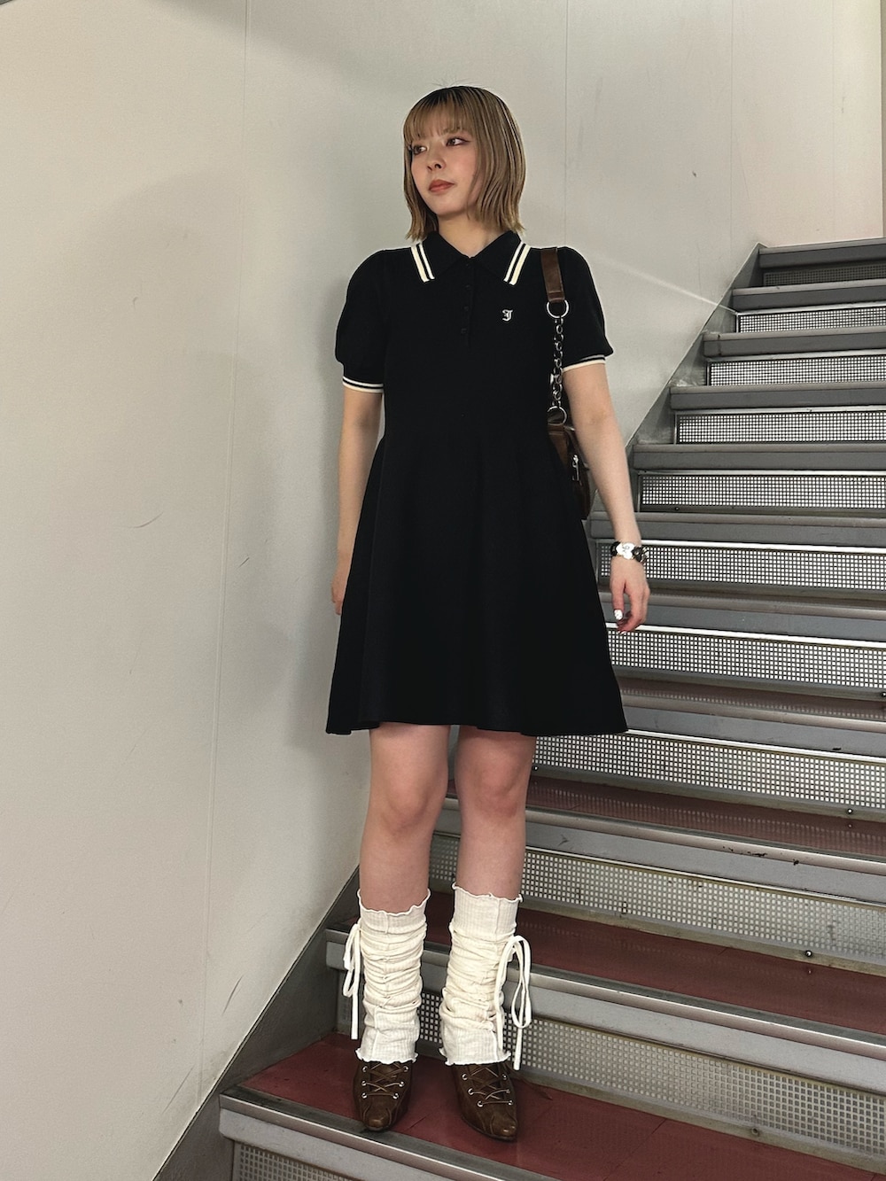 ブラック系のワンピース、ブラウン系のハンドバッグ、ブラウン系のパンプスを着用したレディースの春コーディネートの3枚目の写真