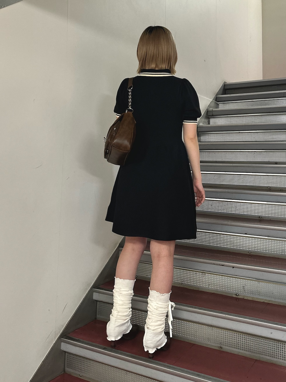 ブラック系のワンピース、ブラウン系のハンドバッグ、ブラウン系のパンプスを着用したレディースの春コーディネートの5枚目の写真