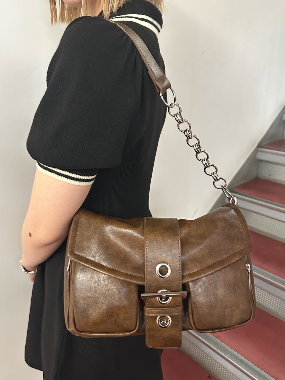 ブラック系のワンピース、ブラウン系のハンドバッグ、ブラウン系のパンプスを着用したレディースの春コーディネートの6枚目の写真