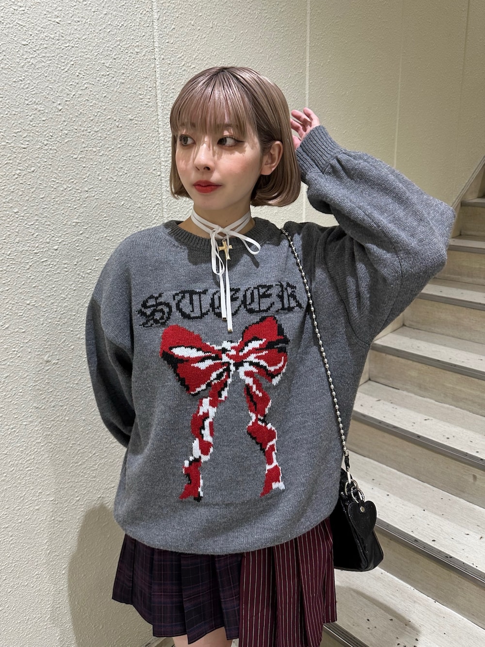 グレー系のニット/セーター、レッド系のスカート、ブラック系のブーツを着用したレディースの冬コーディネートの5枚目の写真