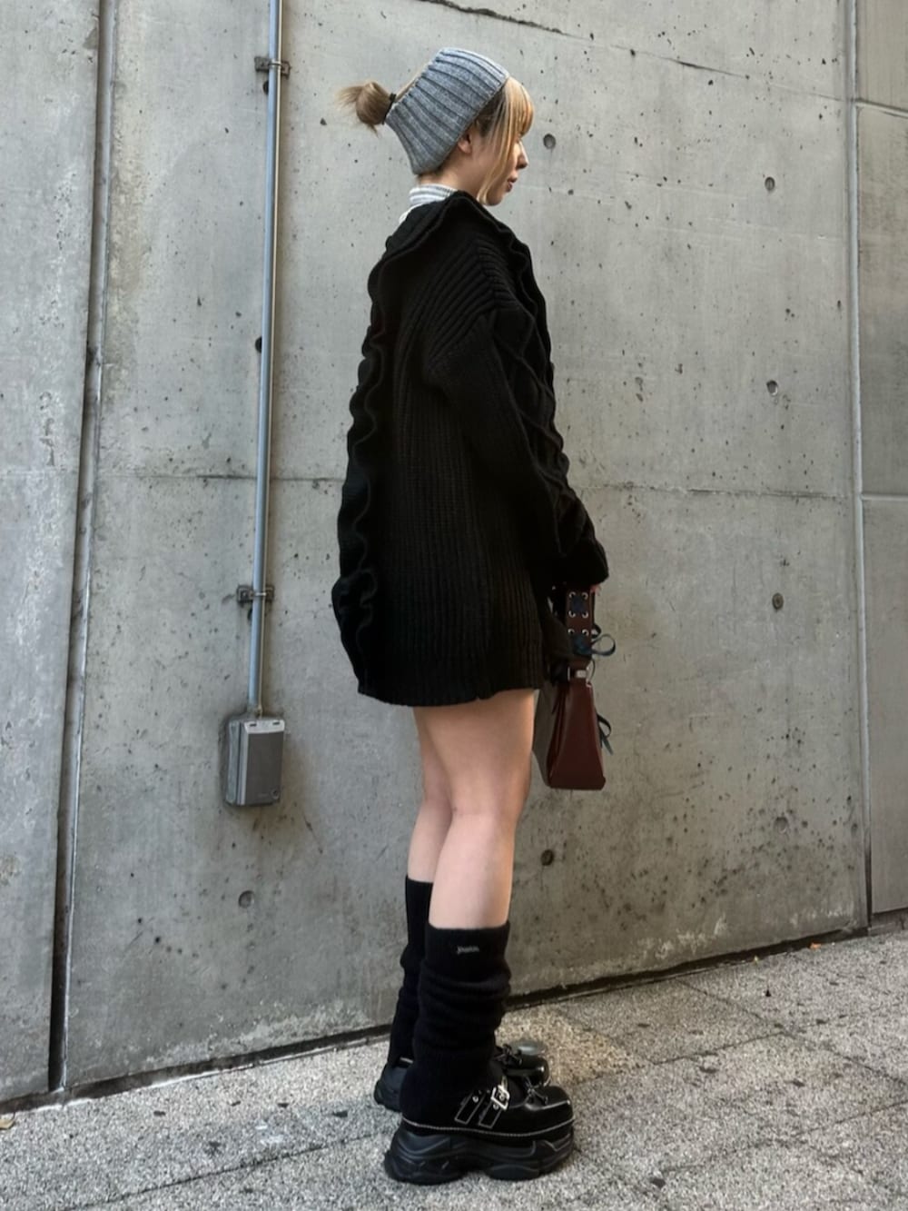 ブラック系のスニーカー、ブラック系のニット/セーター、レッド系のハンドバッグを着用したレディースの冬コーディネートの3枚目の写真