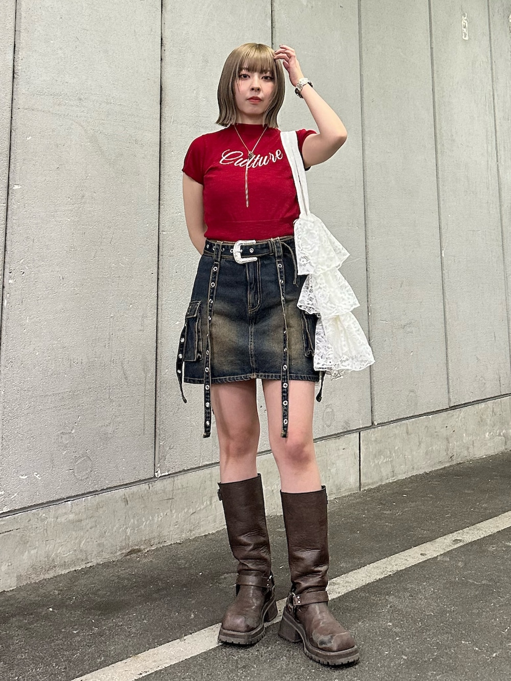 レッド系のニット/セーター、ブルー系のスカート、ブラウン系のブーツを着用したレディースの春コーディネートの2枚目の写真