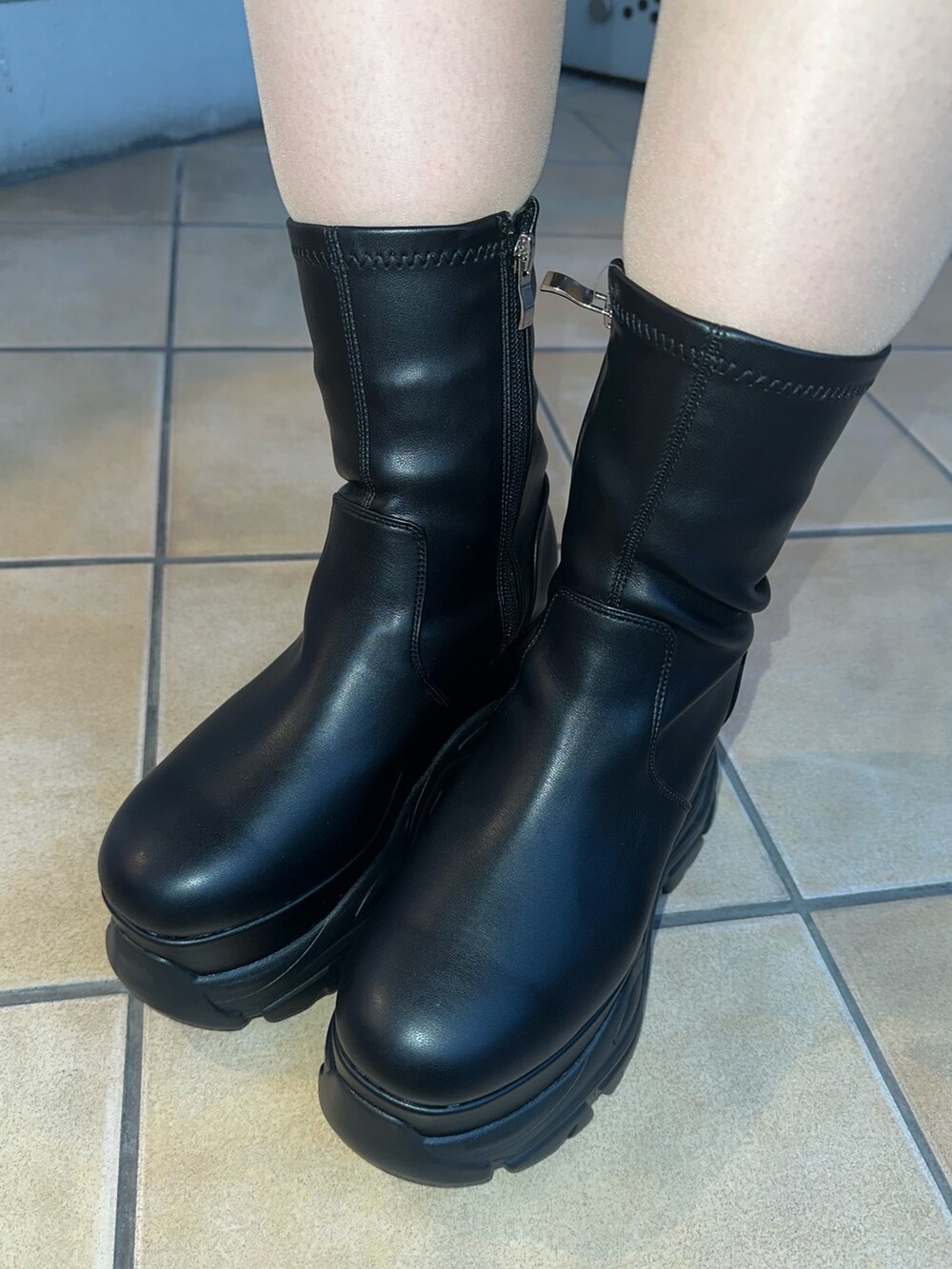 ホワイト系のニット/セーター、ブルー系のスカート、ブラック系のブーツを着用したレディースの冬コーディネートの8枚目の写真