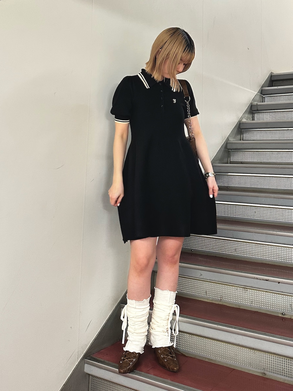 ブラック系のワンピース、ブラウン系のハンドバッグ、ブラウン系のパンプスを着用したレディースの春コーディネートの2枚目の写真