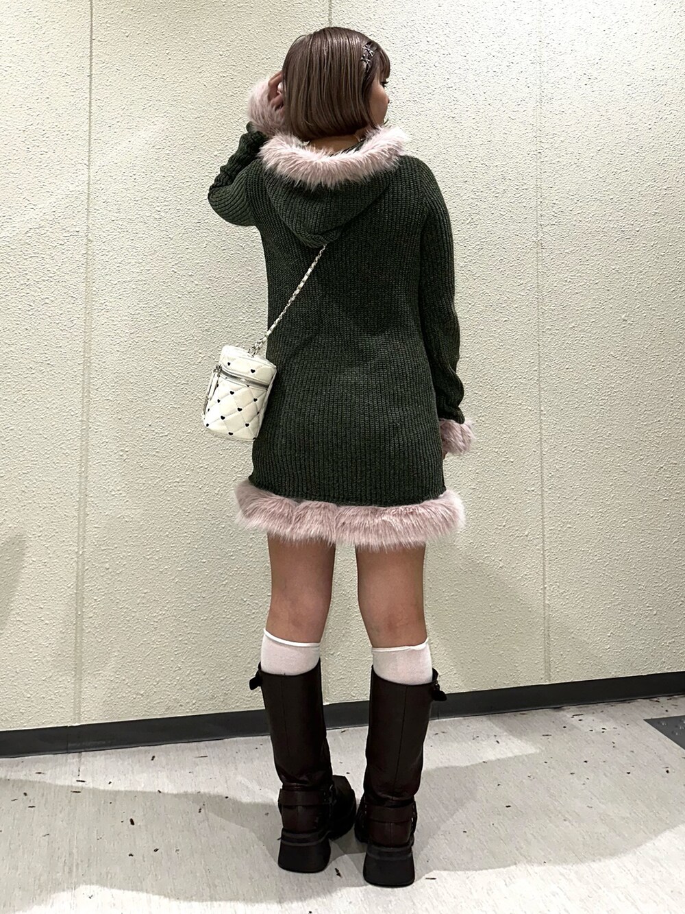 グリーン系のワンピース、ホワイト系のショルダーバッグ、ブラウン系のブーツを着用したレディースの秋コーディネートの2枚目の写真