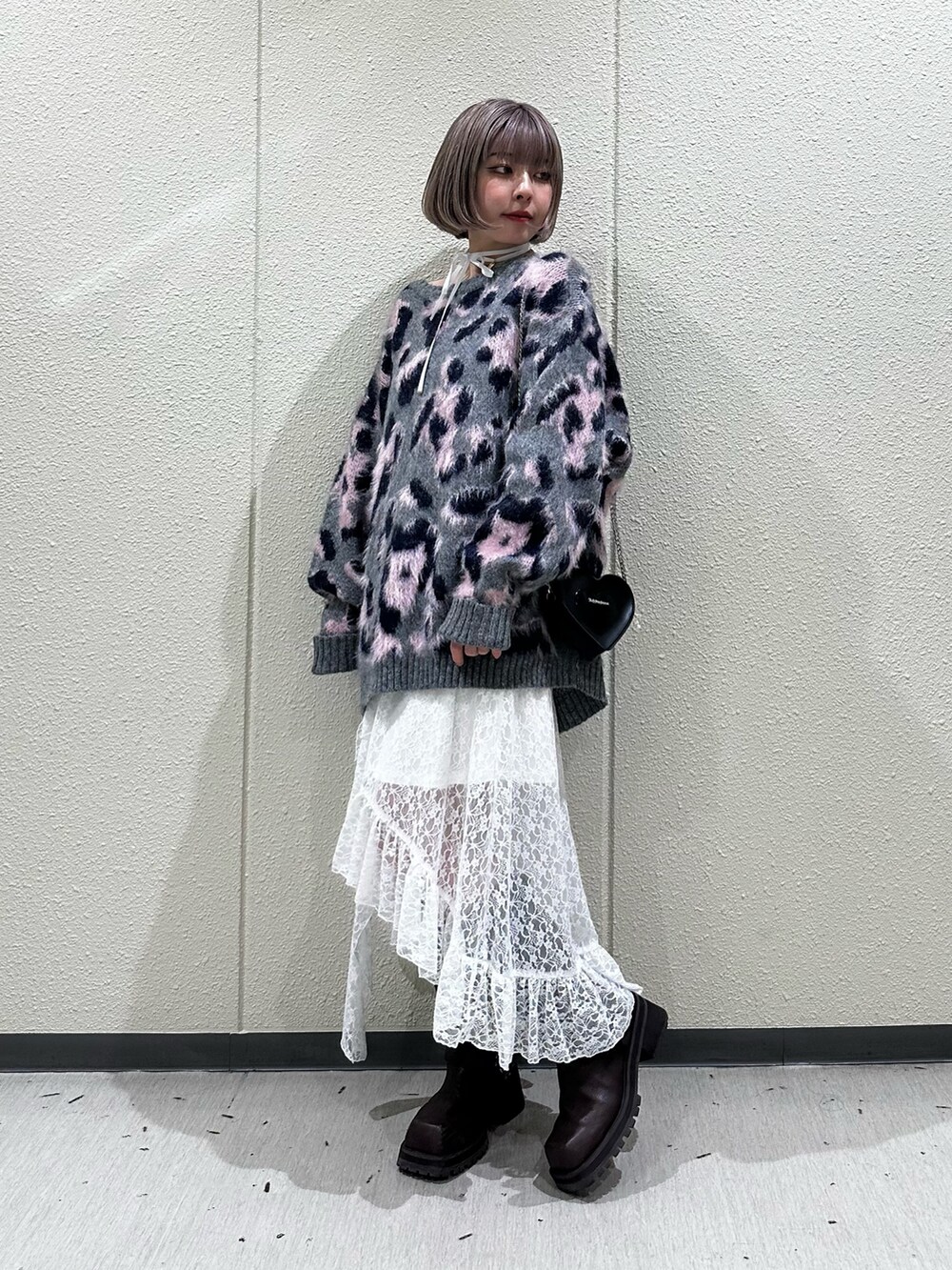 グレー系のニット/セーター、ホワイト系のスカート、ブラウン系のブーツを着用したレディースの秋コーディネートの10枚目の写真