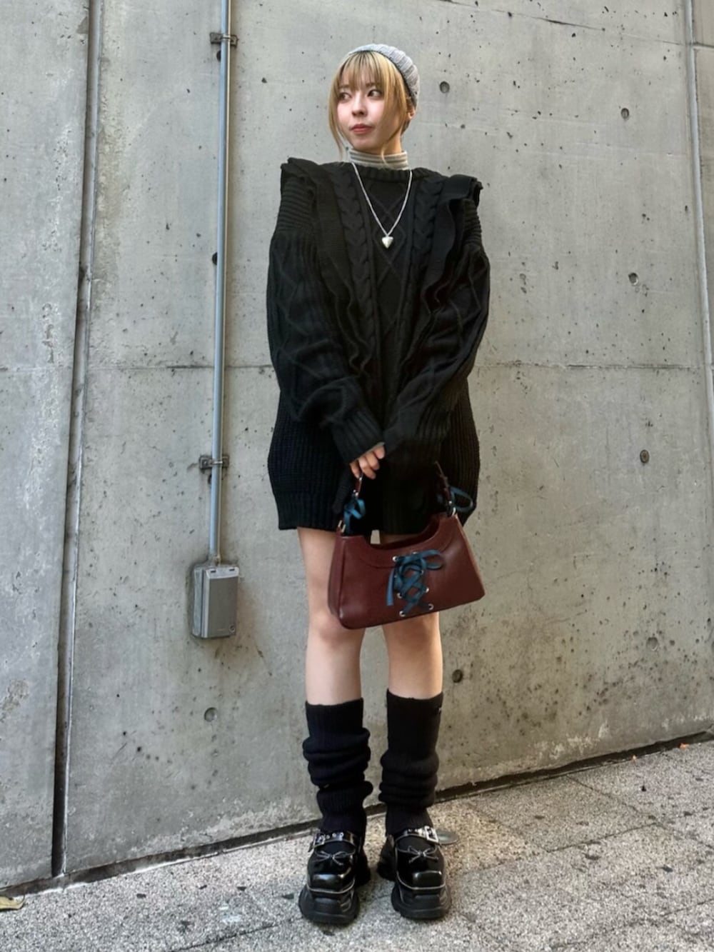 ブラック系のスニーカー、ブラック系のニット/セーター、レッド系のハンドバッグを着用したレディースの冬コーディネートの2枚目の写真