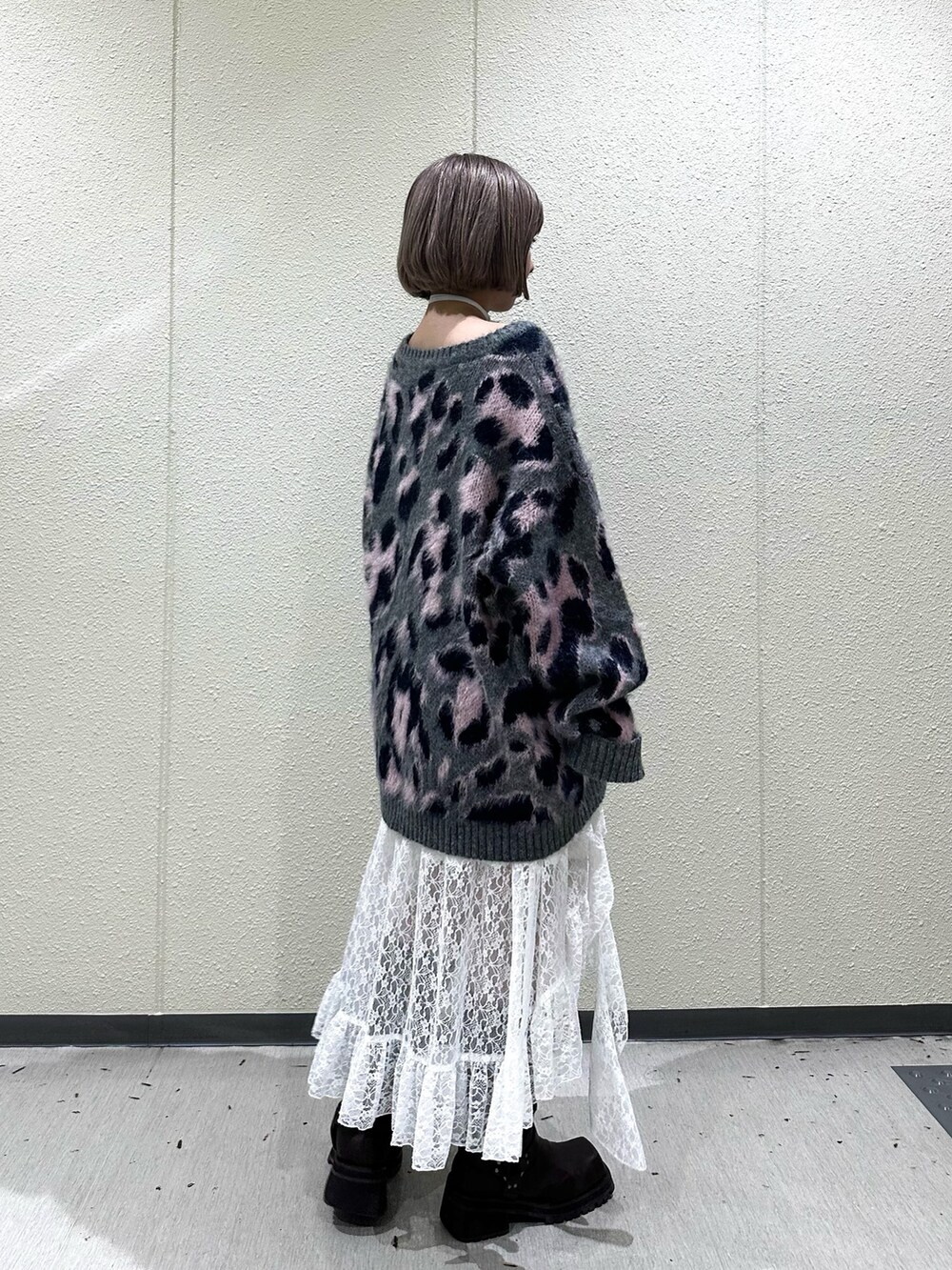 グレー系のニット/セーター、ホワイト系のスカート、ブラウン系のブーツを着用したレディースの秋コーディネートの3枚目の写真