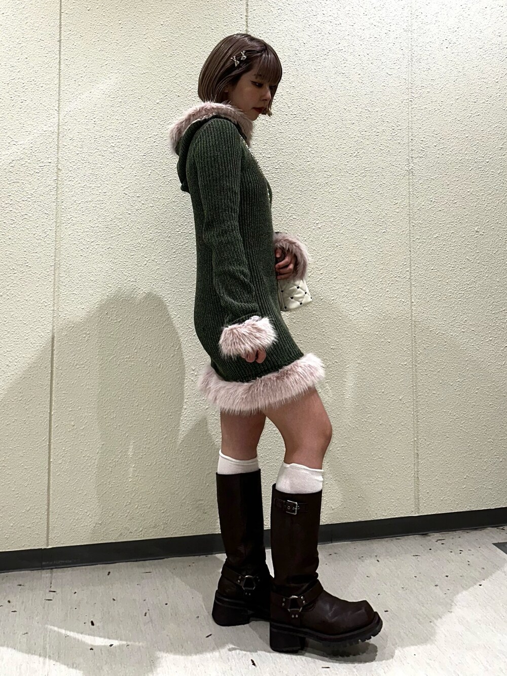 グリーン系のワンピース、ホワイト系のショルダーバッグ、ブラウン系のブーツを着用したレディースの秋コーディネートの3枚目の写真