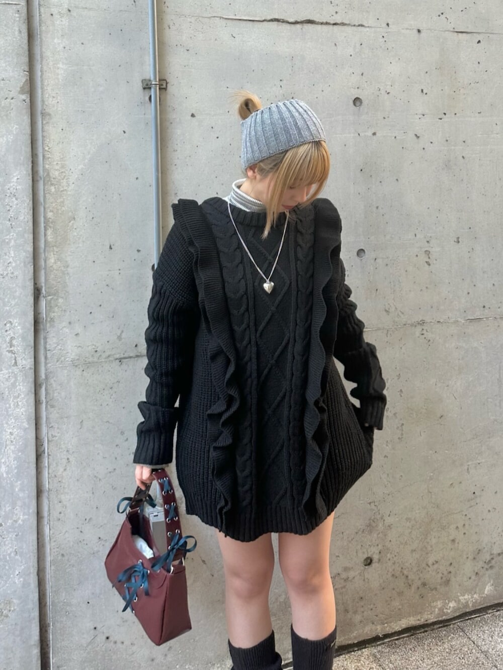 ブラック系のスニーカー、ブラック系のニット/セーター、レッド系のハンドバッグを着用したレディースの冬コーディネートの5枚目の写真