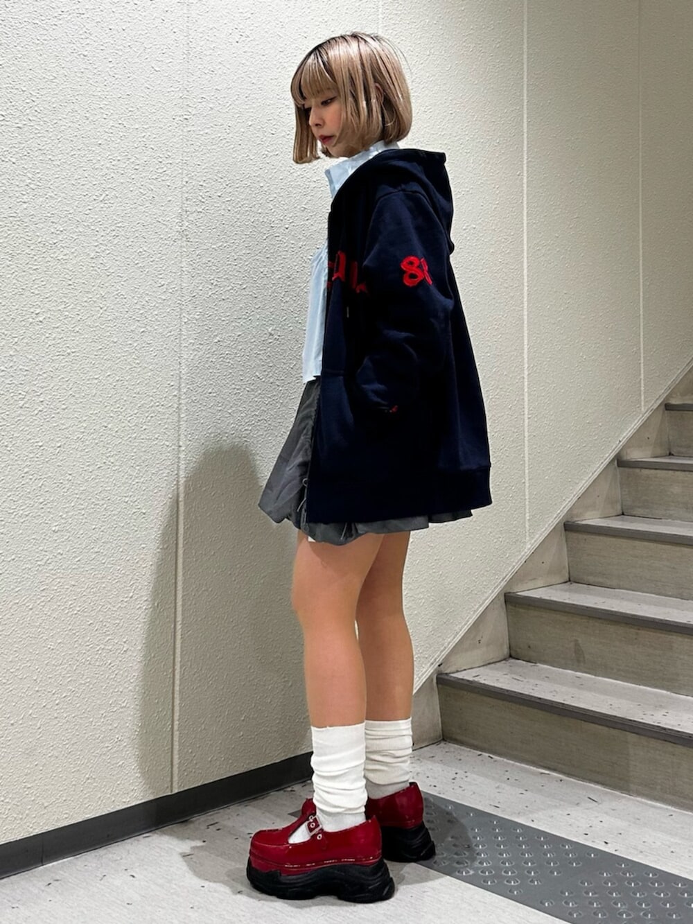 グレー系のスカート、ブルー系のシャツ/ブラウス、レッド系のローファーを着用したレディースの冬コーディネートの2枚目の写真