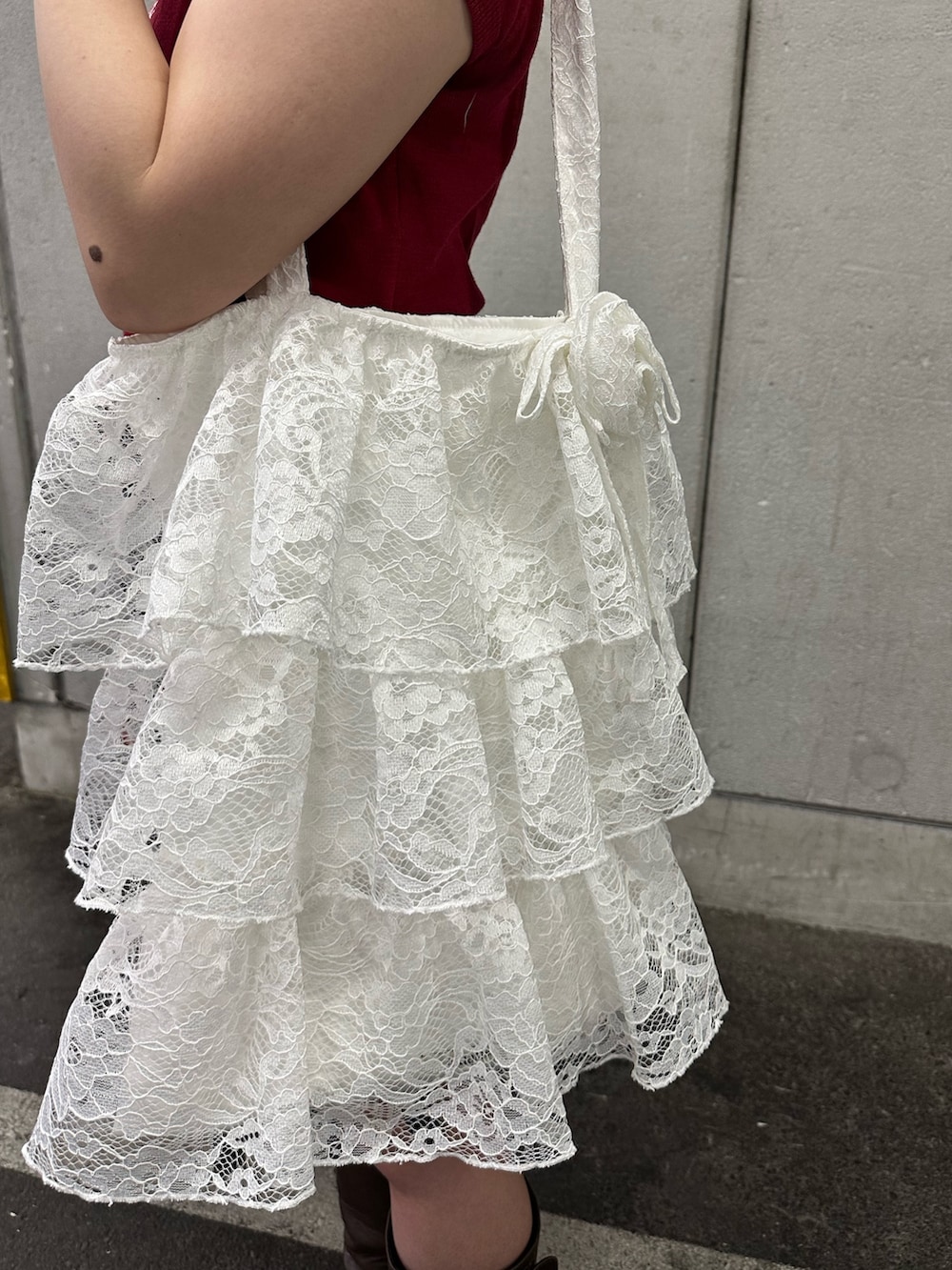 レッド系のニット/セーター、ブルー系のスカート、ブラウン系のブーツを着用したレディースの春コーディネートの10枚目の写真