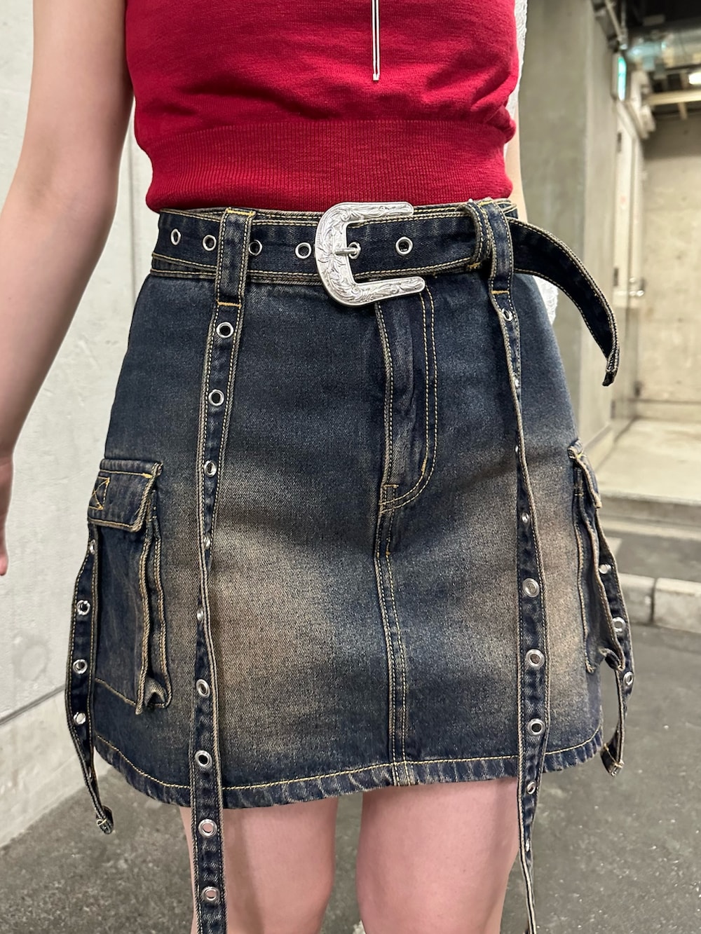 レッド系のニット/セーター、ブルー系のスカート、ブラウン系のブーツを着用したレディースの春コーディネートの9枚目の写真