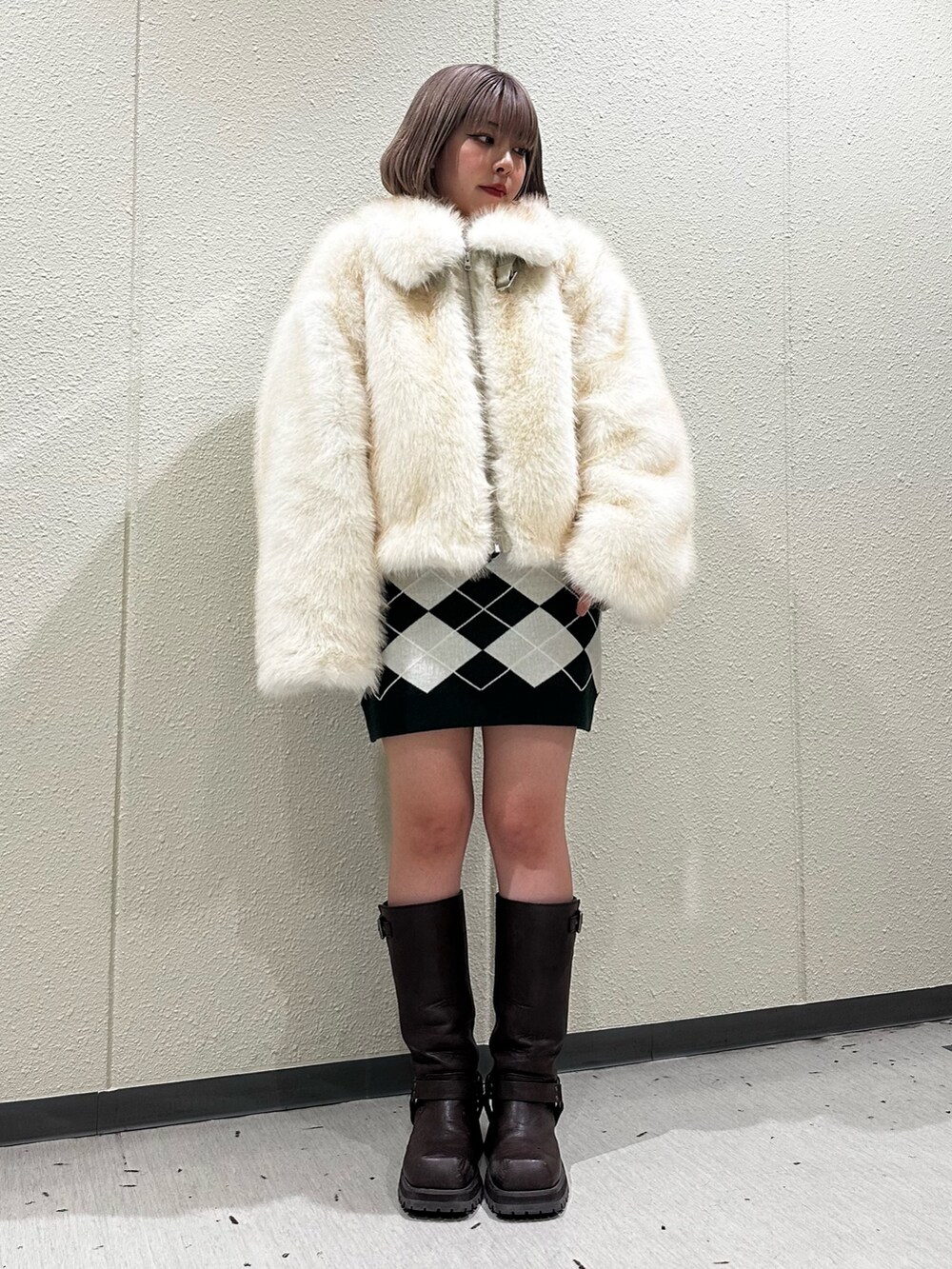 グリーン系のワンピース、ブラウン系のブーツ、ホワイト系のその他アウターを着用したレディースの秋コーディネートの2枚目の写真