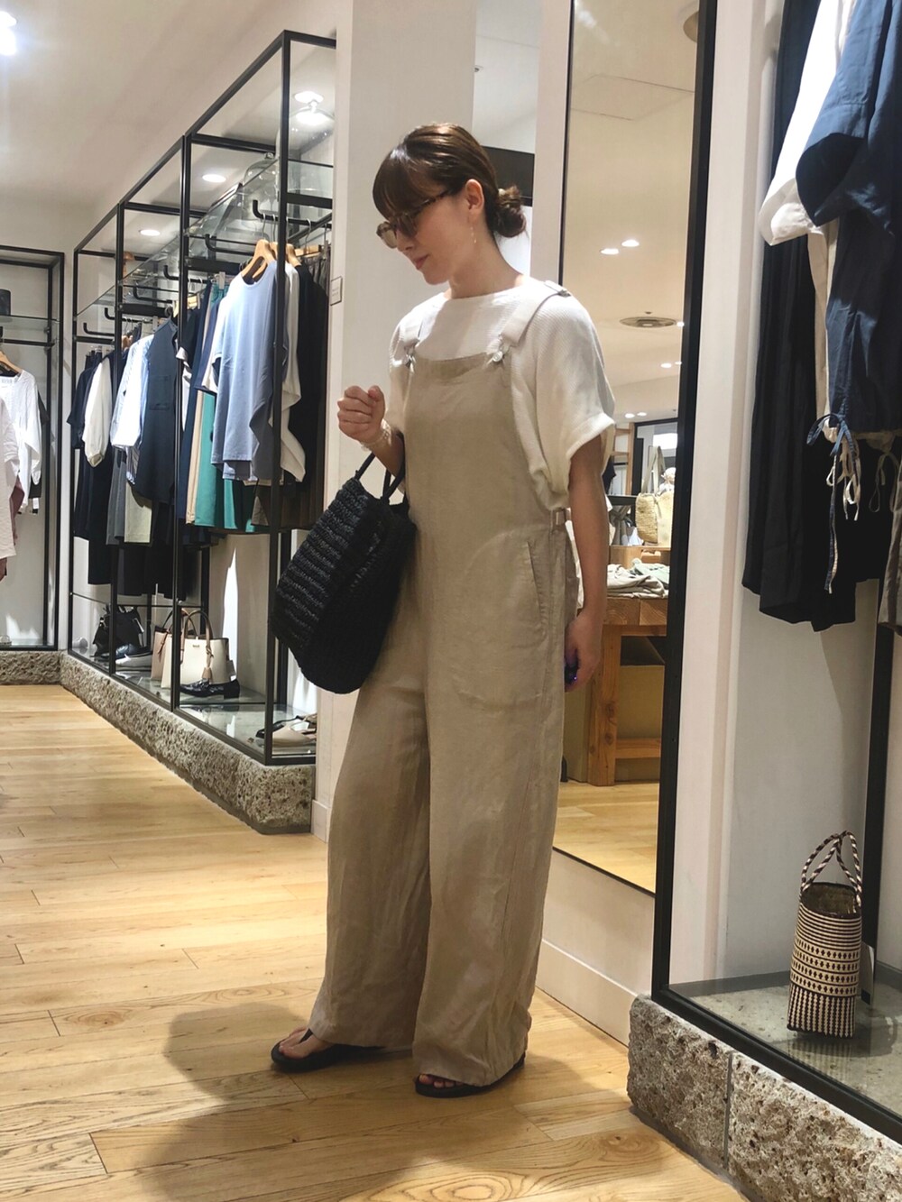 ブラック系のトートバッグ、ベージュ系のサロペット/オーバーオール、ホワイト系のTシャツ/カットソーを着用したレディースの夏コーディネートの4枚目の写真