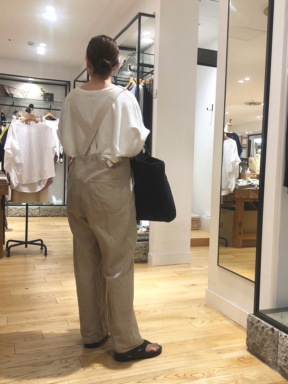 ブラック系のトートバッグ、ベージュ系のサロペット/オーバーオール、ホワイト系のTシャツ/カットソーを着用したレディースの夏コーディネートの3枚目の写真