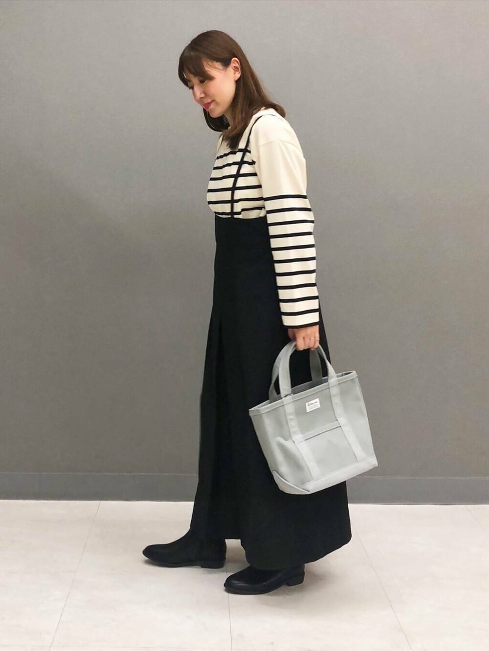 ホワイト系のTシャツ/カットソー、ブラック系のブーツ、ブラック系のワンピースを着用したレディースの秋コーディネートの2枚目の写真