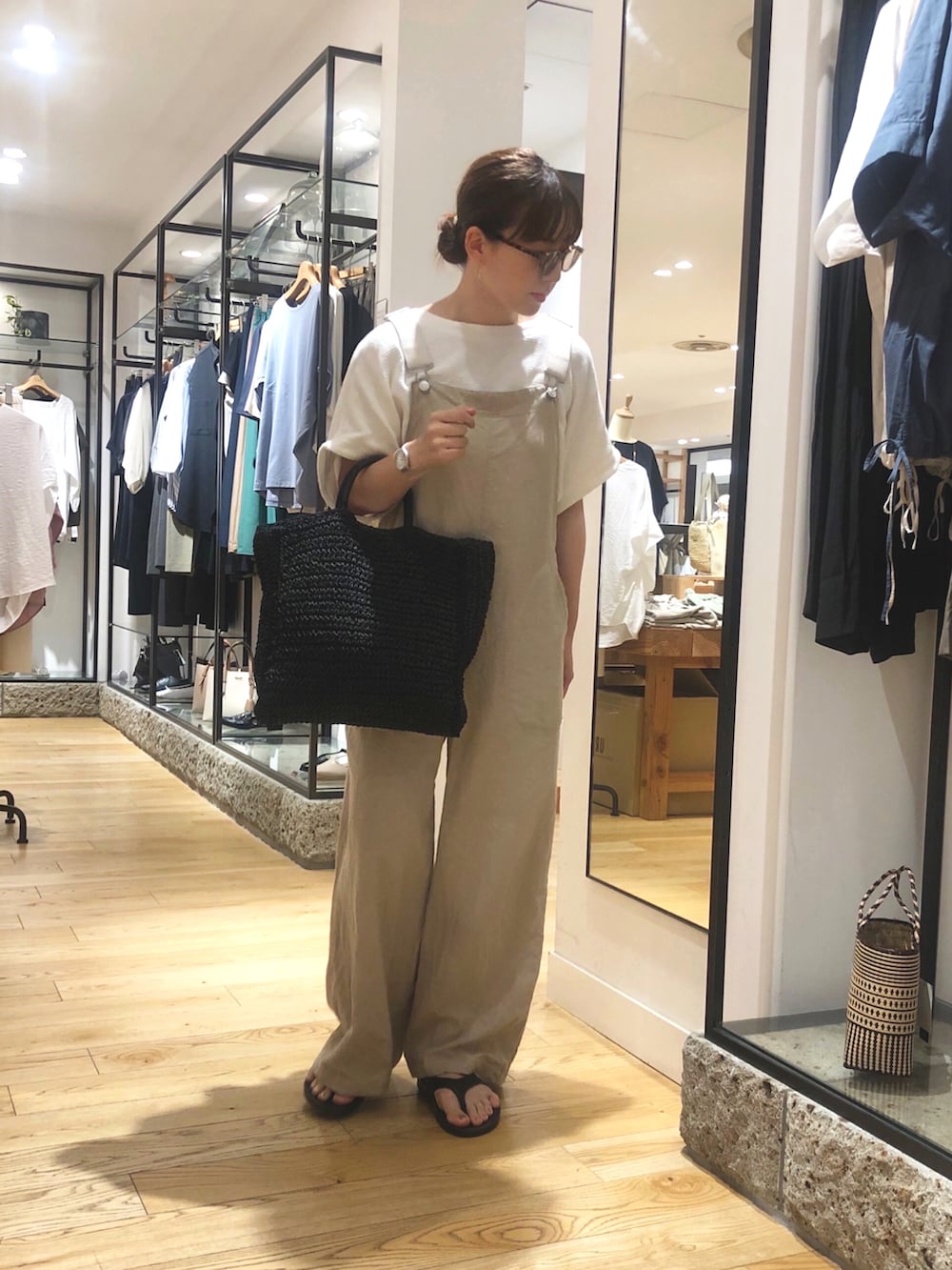 ブラック系のトートバッグ、ベージュ系のサロペット/オーバーオール、ホワイト系のTシャツ/カットソーを着用したレディースの夏コーディネートの2枚目の写真