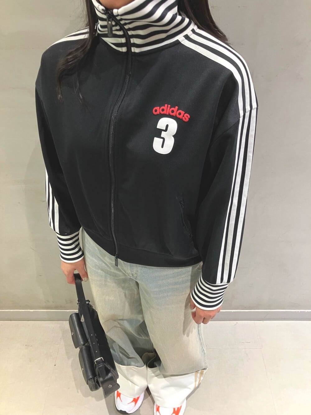 ブラック系のジャージ、ブルー系のデニムパンツ、ホワイト系のスニーカーを着用したレディースの冬コーディネートの2枚目の写真