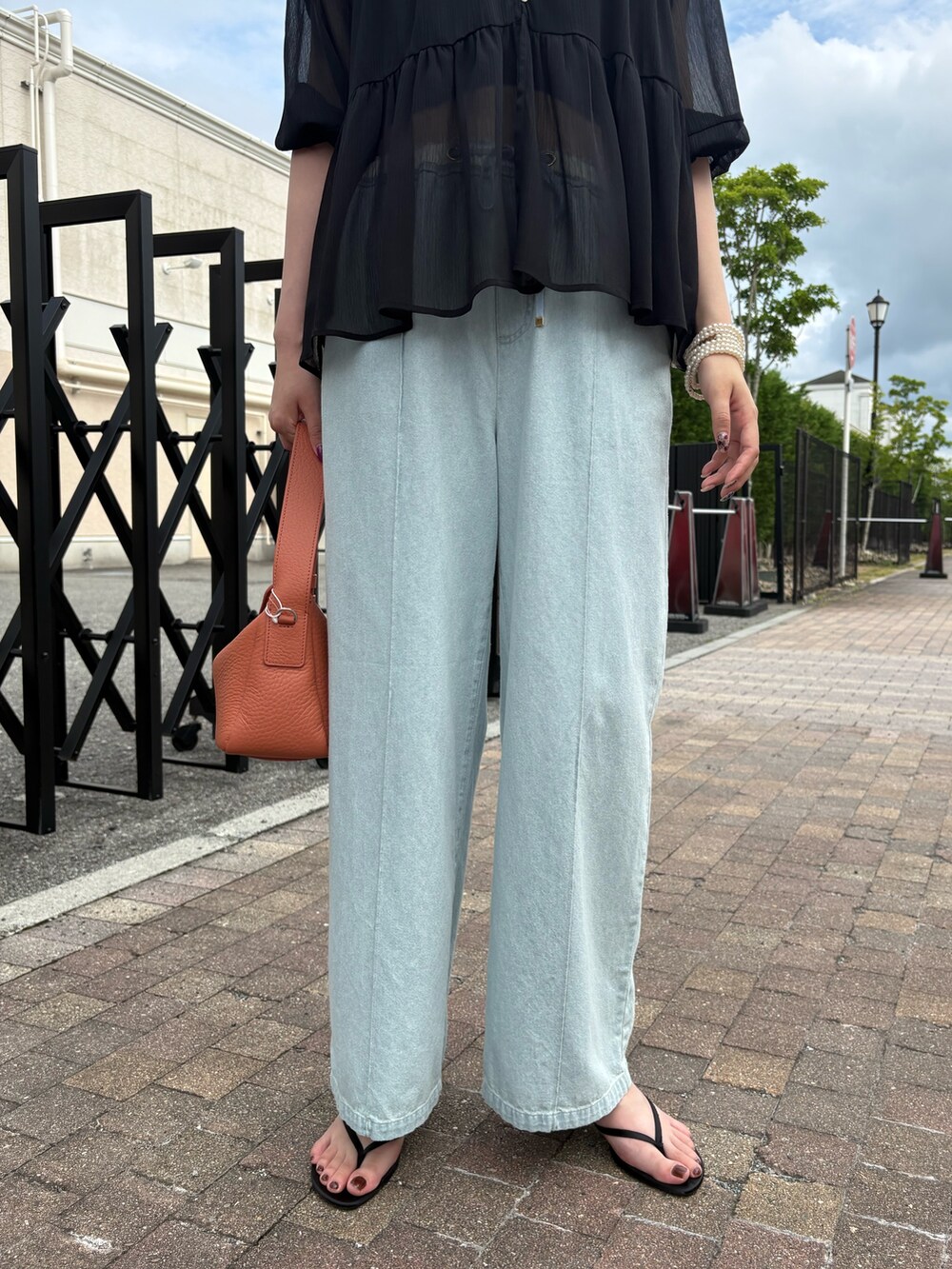ブラック系のシャツ/ブラウス、ブルー系のデニムパンツを着用したレディースの夏コーディネートの2枚目の写真