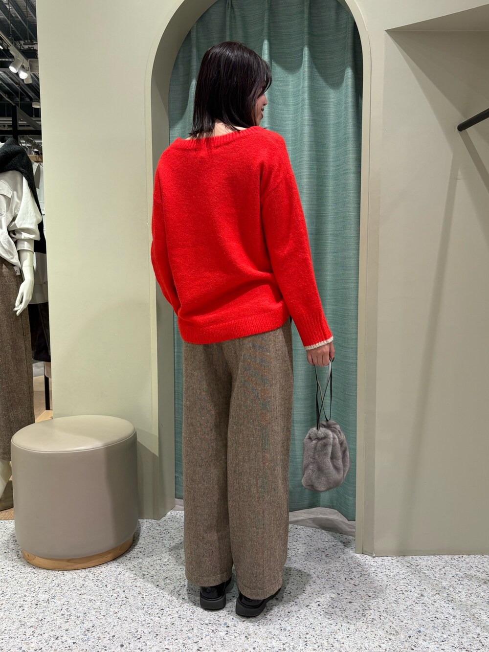 レッド系のニット/セーター、ブラウン系のその他パンツ、ブラック系のトートバッグを着用したレディースの秋コーディネートの2枚目の写真