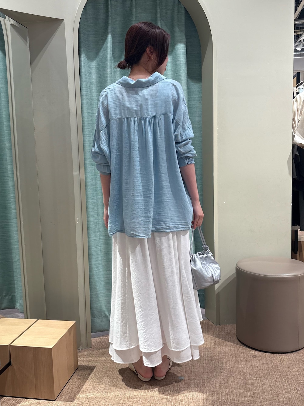 ブルー系のシャツ/ブラウス、ホワイト系のスカート、シルバー系のトートバッグを着用したレディースの春コーディネートの2枚目の写真