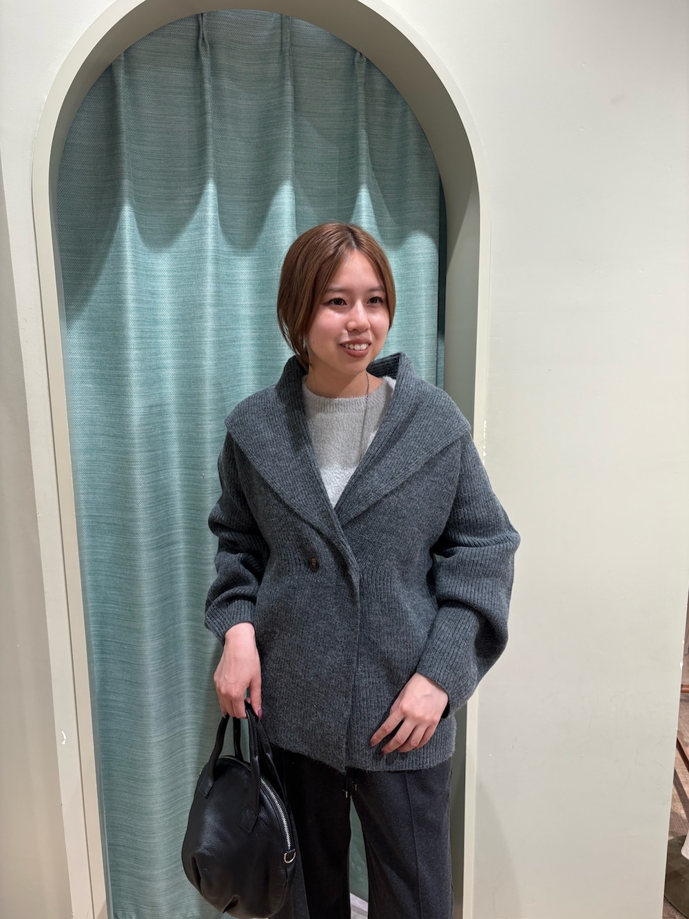 グレー系のニット/セーター、ブラック系のトートバッグ、グレー系のその他パンツを着用したレディースの秋コーディネートの4枚目の写真