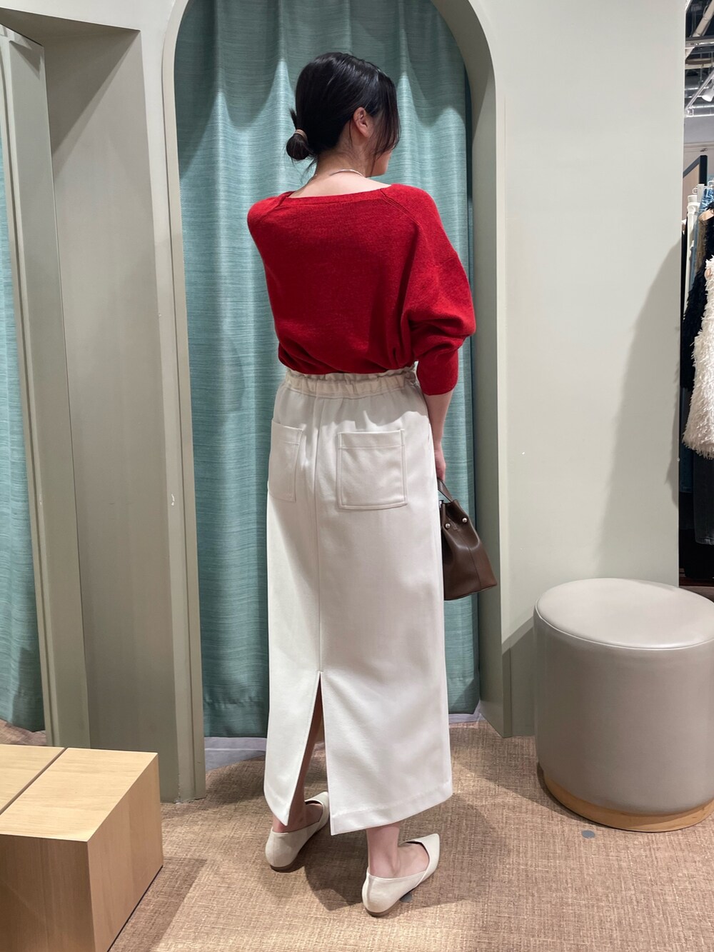レッド系のニット/セーター、ホワイト系のスカート、ホワイト系のパンプスを着用したレディースの秋コーディネートの2枚目の写真