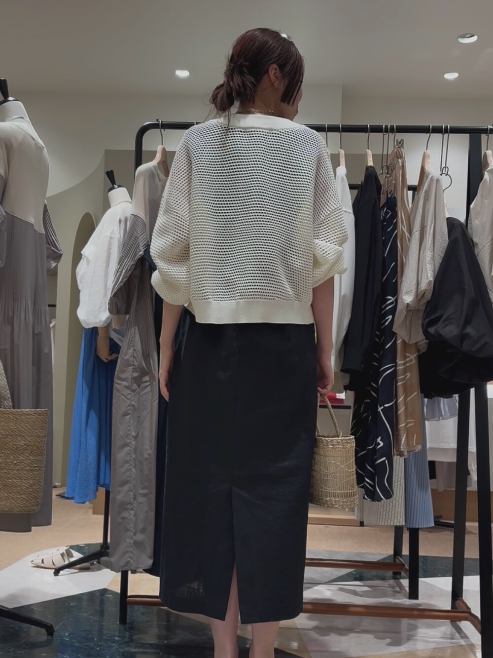 ブラック系のワンピース、ホワイト系のブルゾン、ベージュ系のトートバッグを着用したレディースの春コーディネートの2枚目の写真