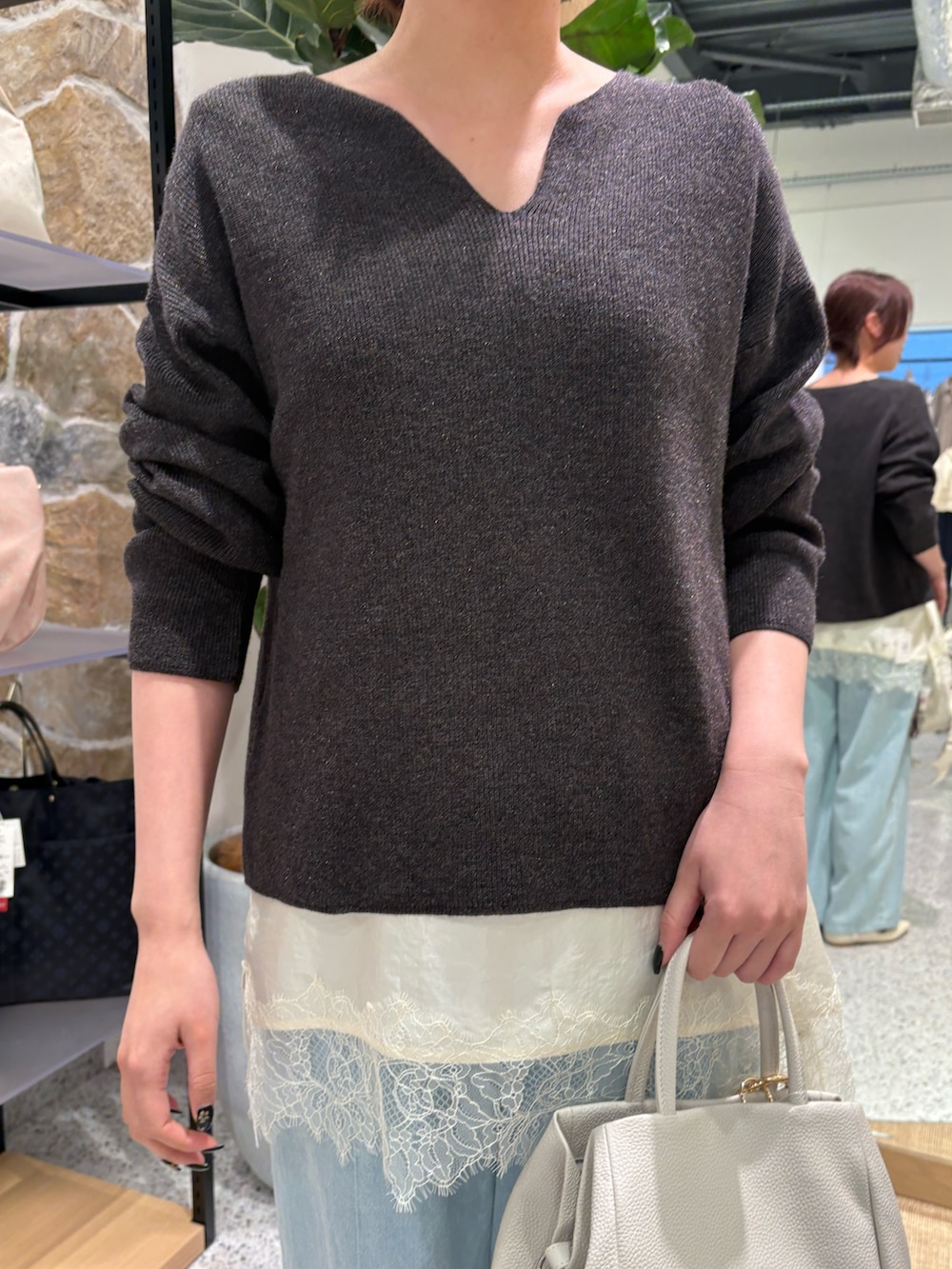 グレー系のニット/セーター、ホワイト系のシャツ/ブラウス、ブルー系のデニムパンツを着用したレディースの春コーディネートの2枚目の写真