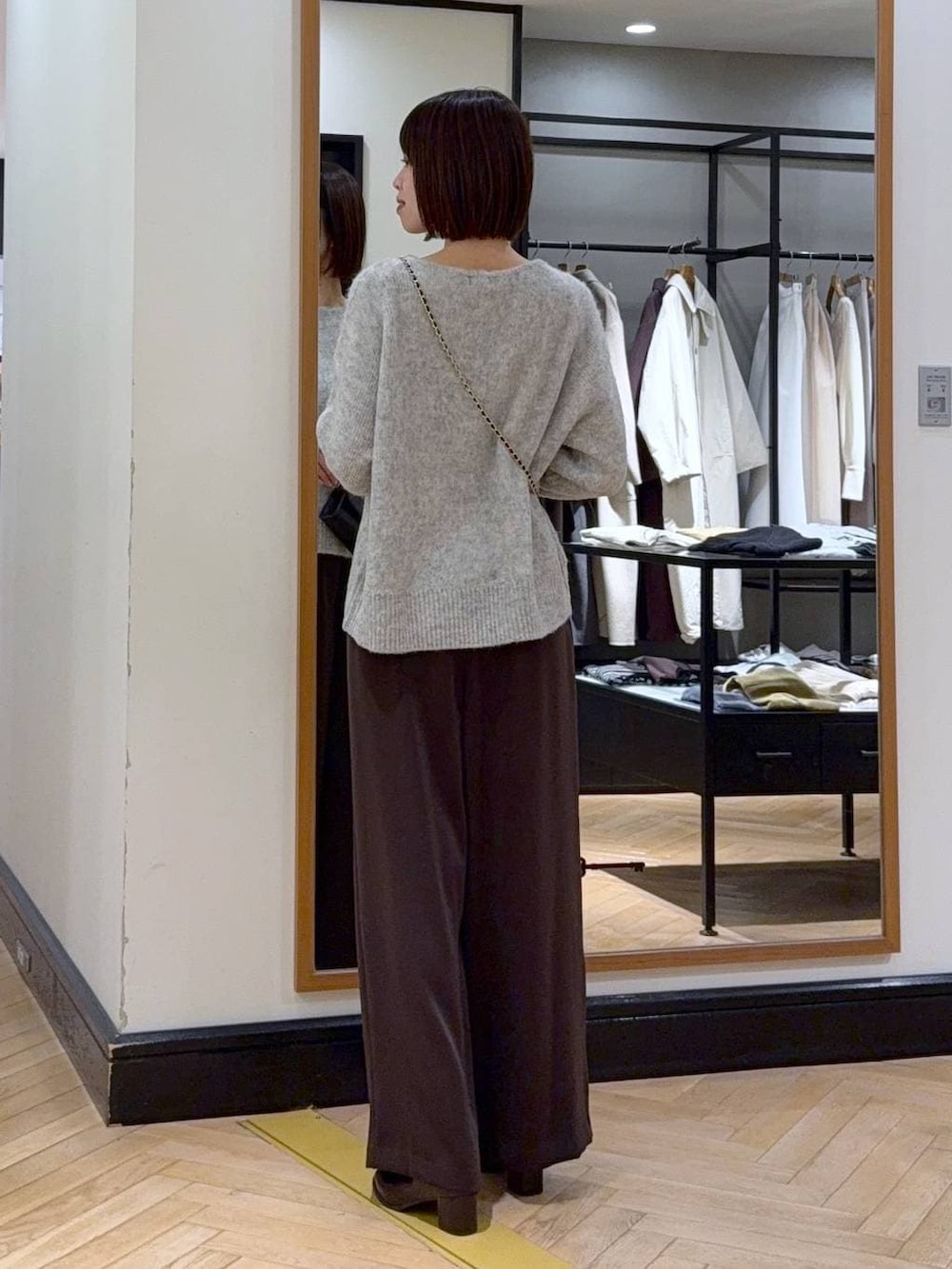 ブラウン系のブーツ、グレー系のニット/セーター、ブラウン系のスラックスを着用したレディースの秋コーディネートの3枚目の写真