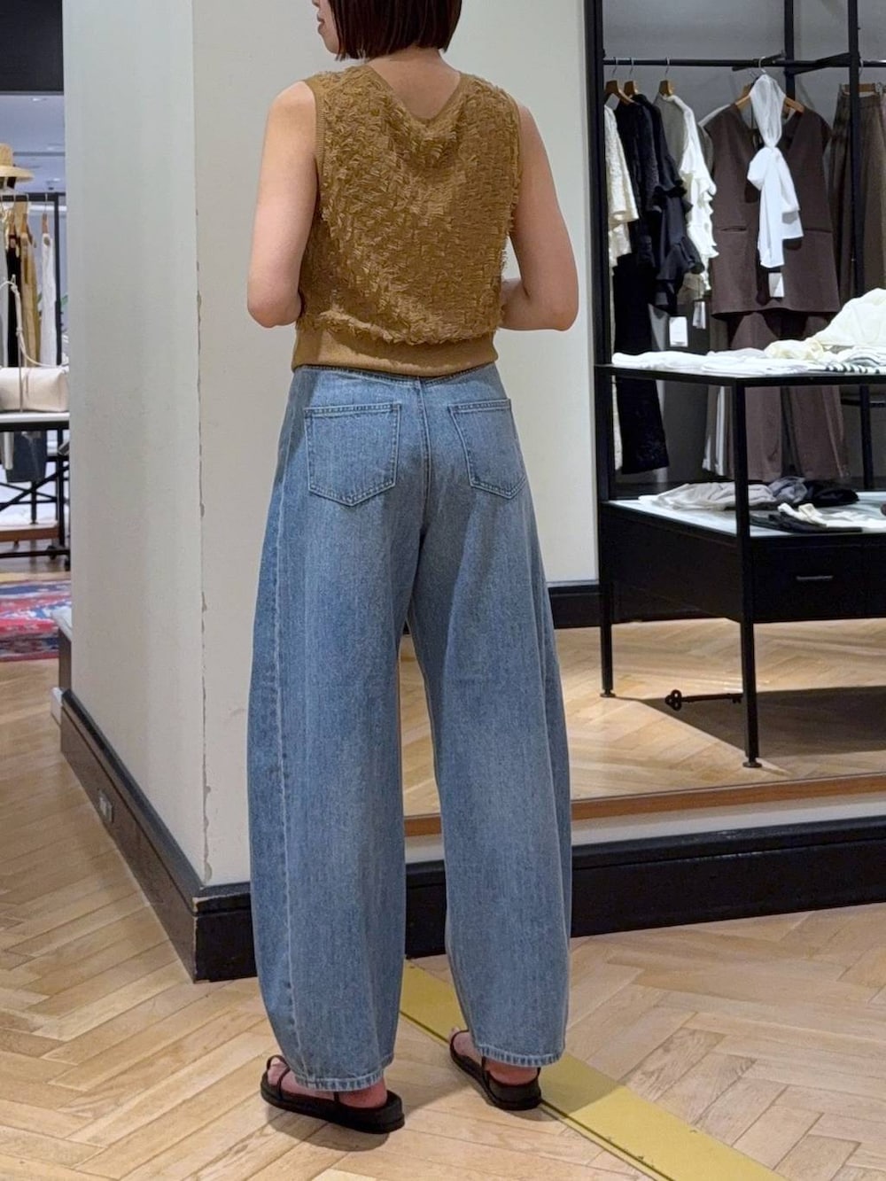 ブルー系のデニムパンツ、ホワイト系のショルダーバッグ、イエロー系のニット/セーターを着用したレディースの夏コーディネートの3枚目の写真