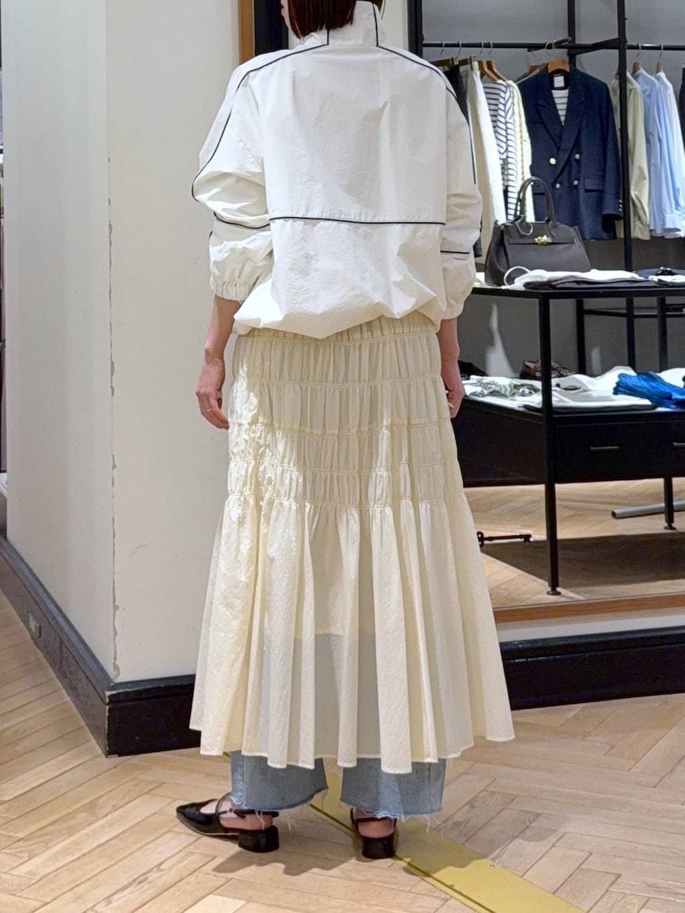 ブラック系のショルダーバッグ、ブルー系のデニムパンツ、ホワイト系のブルゾンを着用したレディースの冬コーディネートの4枚目の写真