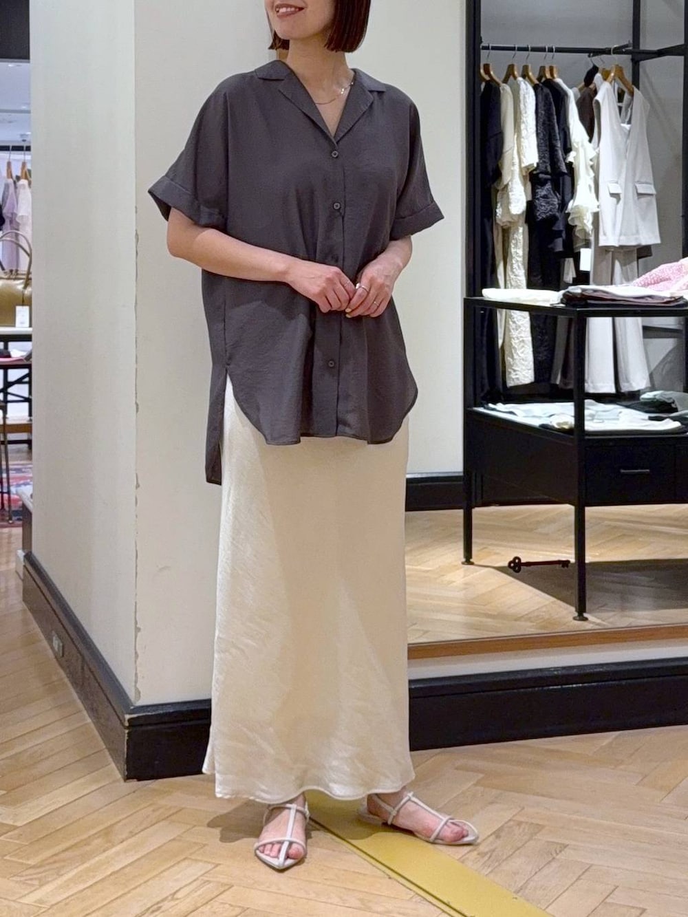 ホワイト系のスカート、ホワイト系のサンダル、グレー系のシャツ/ブラウスを着用したレディースの夏コーディネートの2枚目の写真